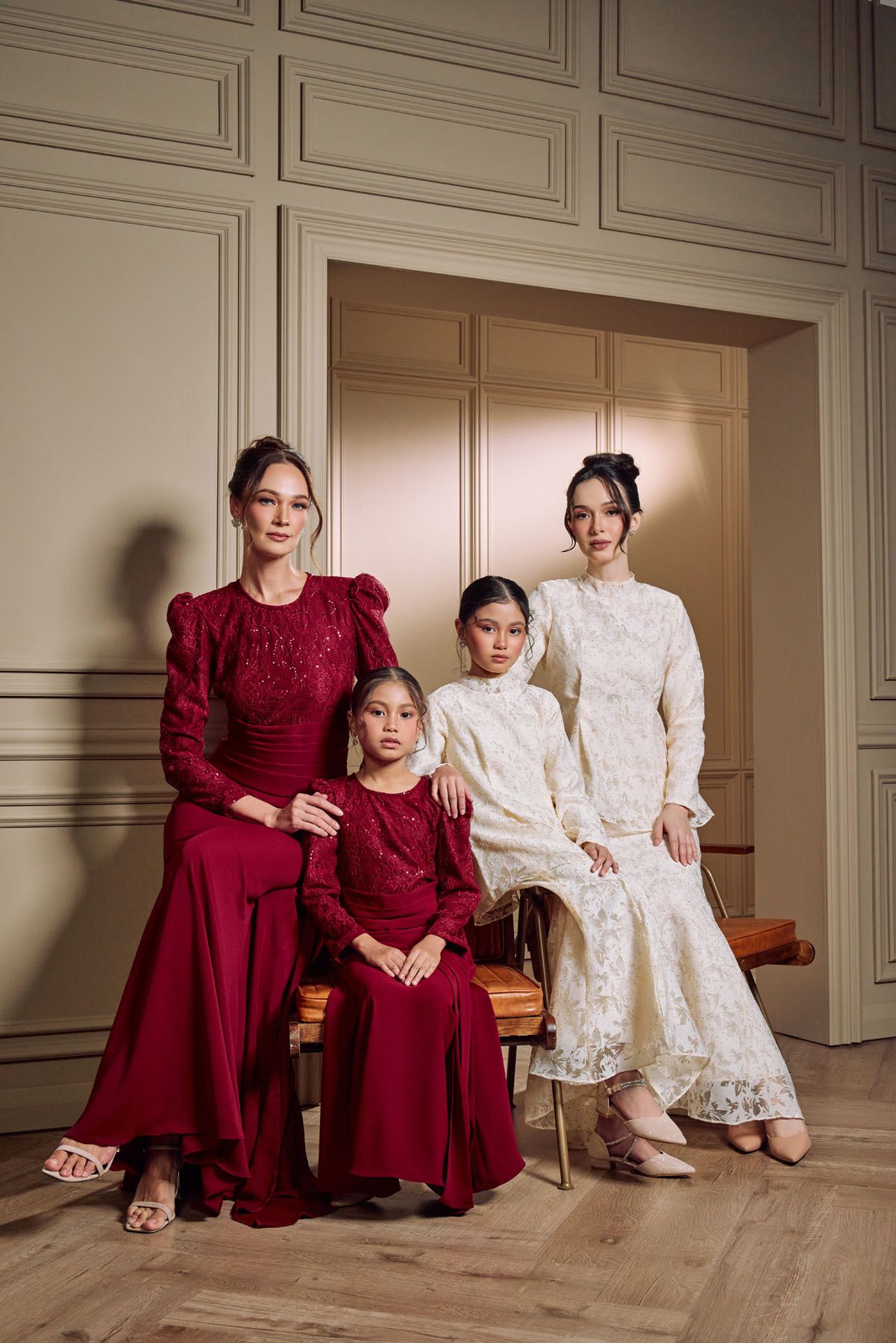 Four women and girls in red and white lace baju kurung pose together.