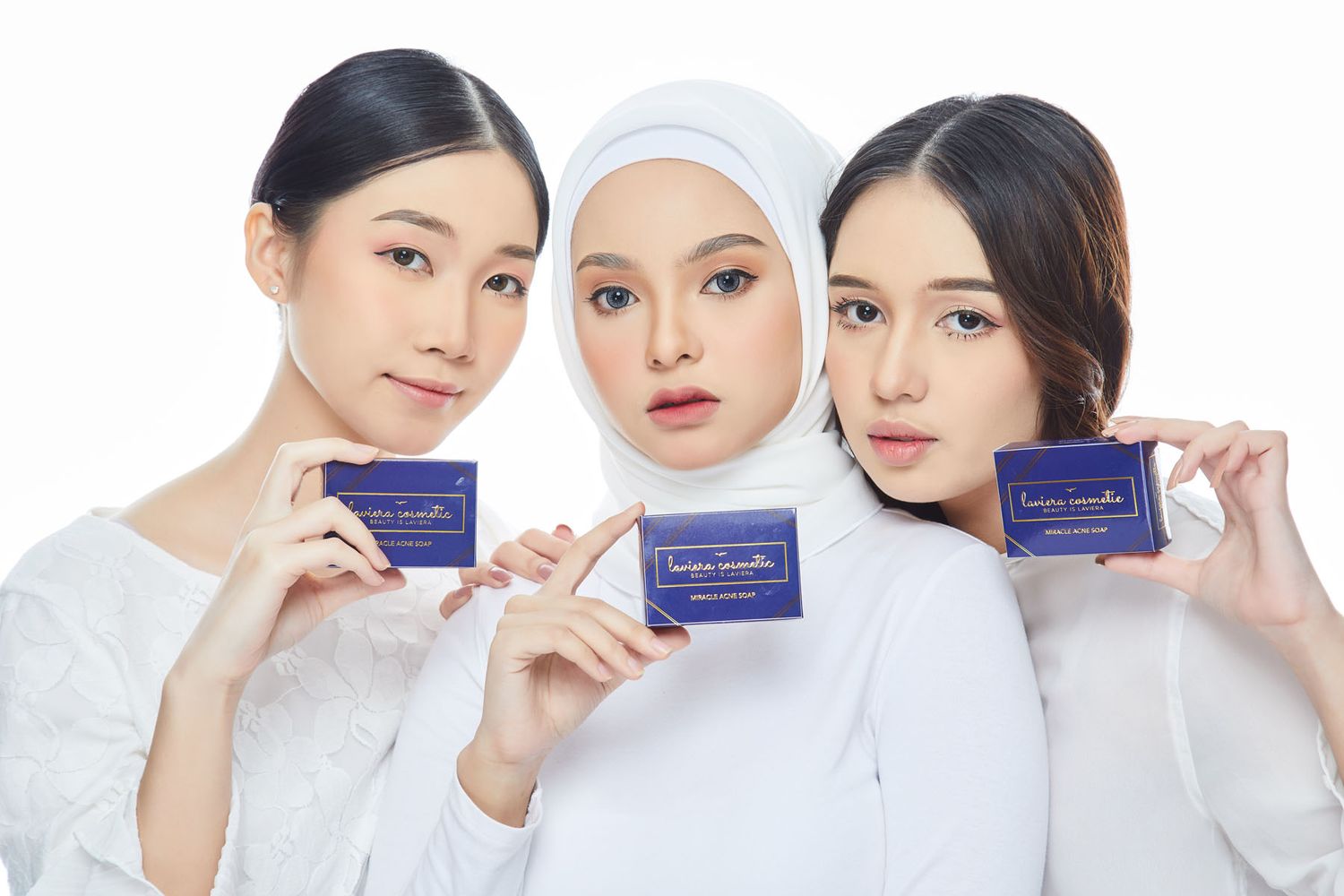 Three women in white holding navy blue product boxes against white background promotional photo.