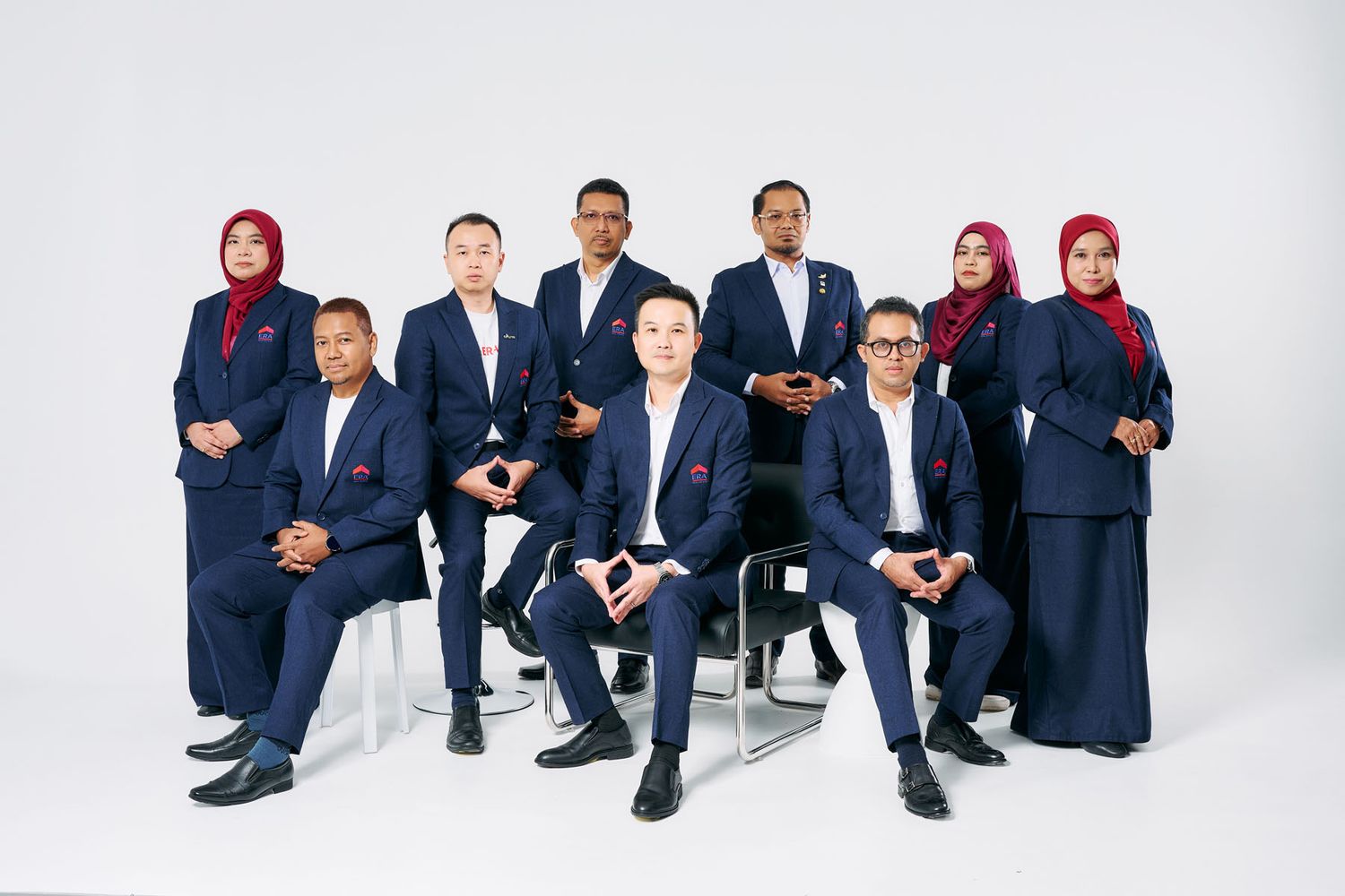 Professional group portrait of nine corporate employees in navy blue uniforms posing against a white background.