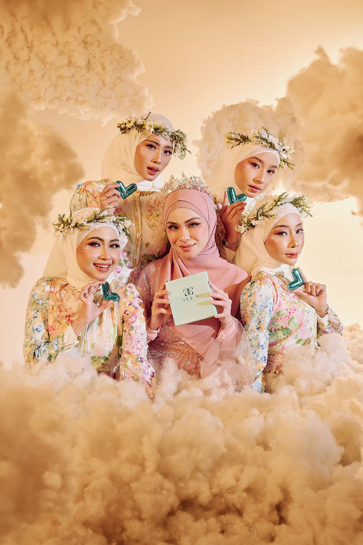Group of five Muslim women in hijabs pose with Ayla Cosmetics Twist lip gloss in golden cloud setting.