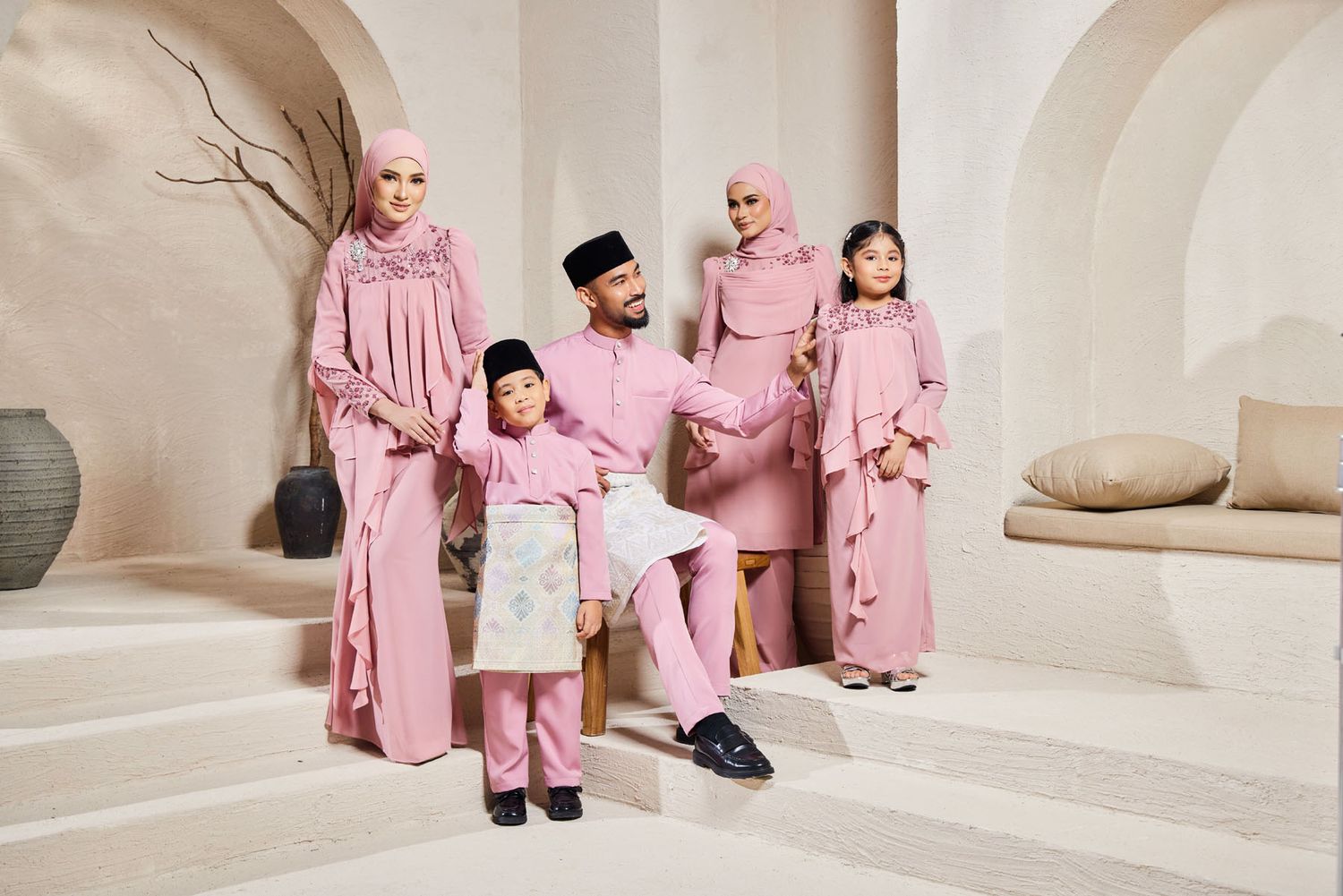 Malaysian family wearing coordinated pink baju kurung and baju melayu traditional Eid festive outfits.