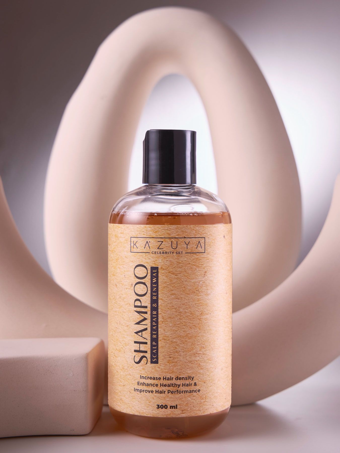KAZUYA Shampoo 300ml golden bottle for hair density and healthy hair displayed against sculptural beige prop.