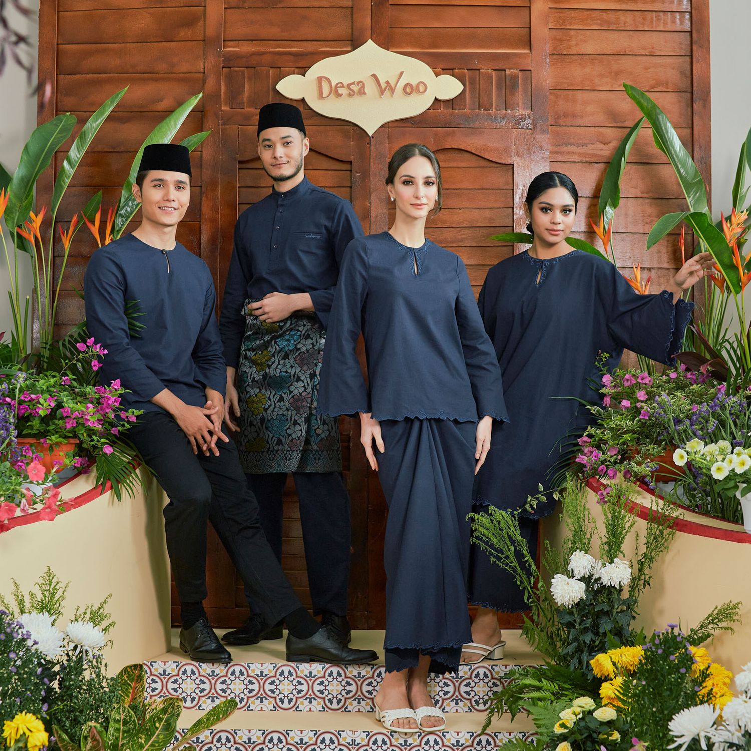 Group of four wearing matching navy blue traditional Malay baju kurung and baju melayu outfits.