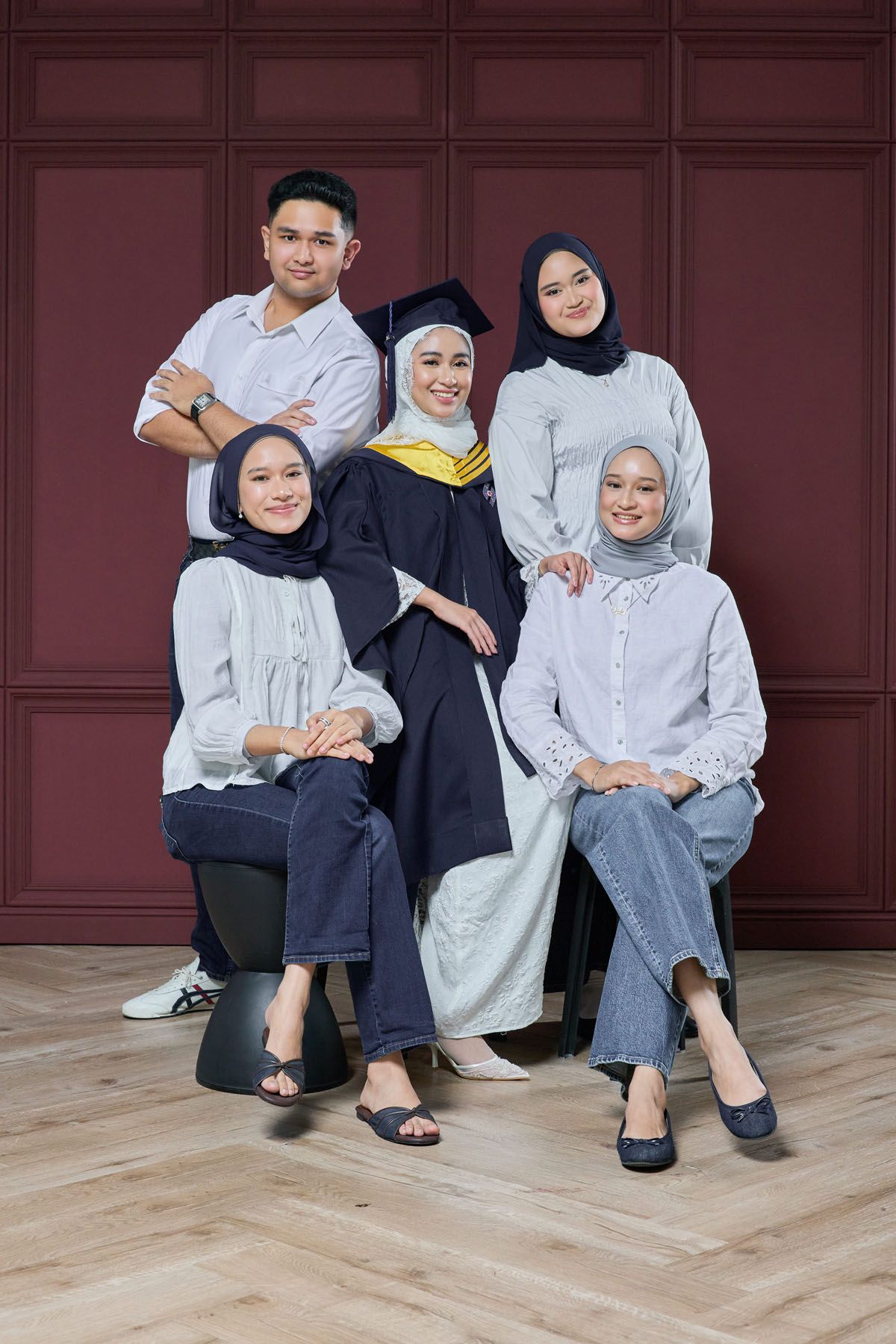 Group of five young Muslims posing with graduate in navy gown and mortarboard cap.