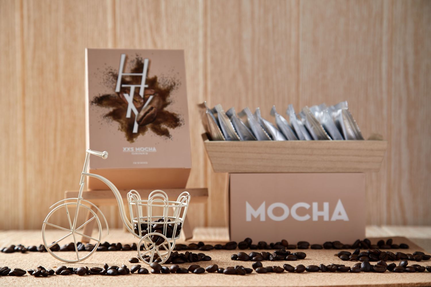 Mocha brand coffee packets displayed in a box with coffee beans and a decorative bicycle figurine.