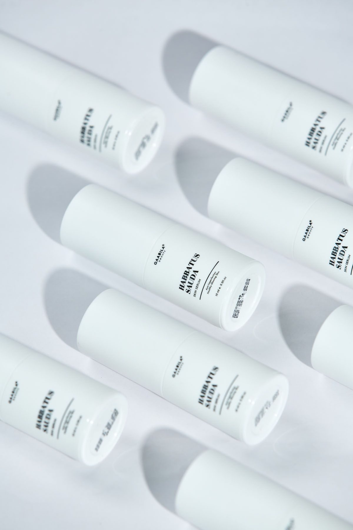 Multiple white Habbatus Sauda skincare tubes arranged diagonally on a light gray background with soft shadows.