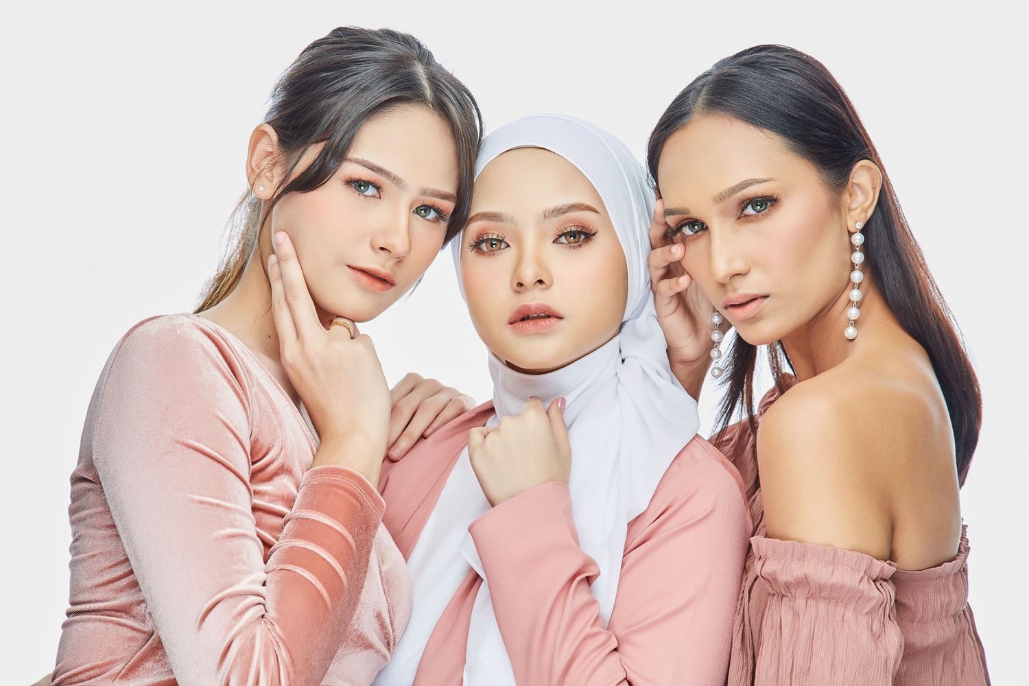 Three stylish women in pink and white outfits posing confidently for a fashion beauty campaign.