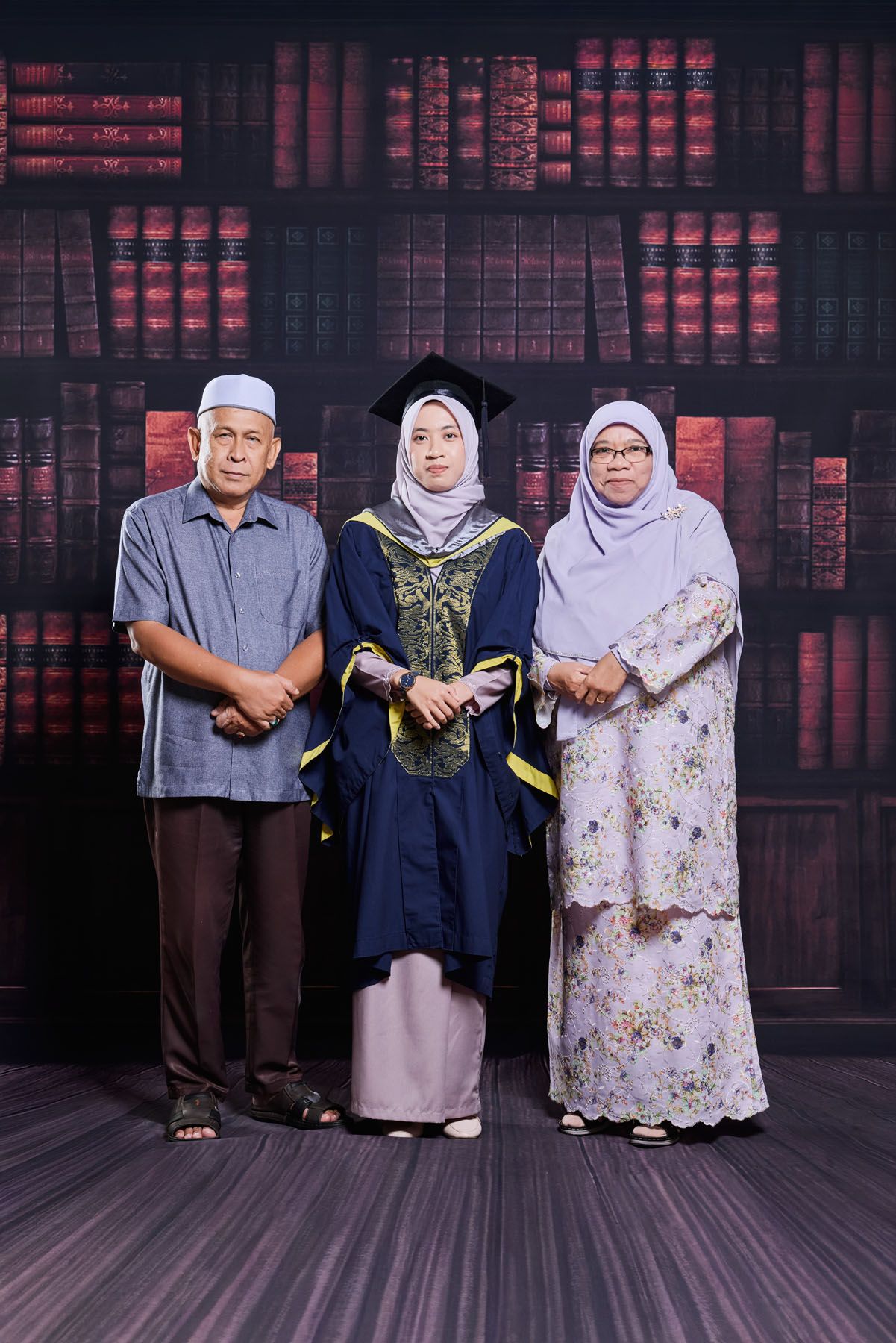 Muslim family portrait with graduate daughter in navy blue robe and mortarboard cap at ceremony.