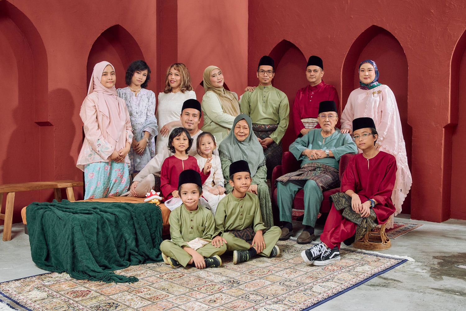 Malaysian family in traditional Baju Melayu and Baju Kurung posing together for Eid celebration photo.