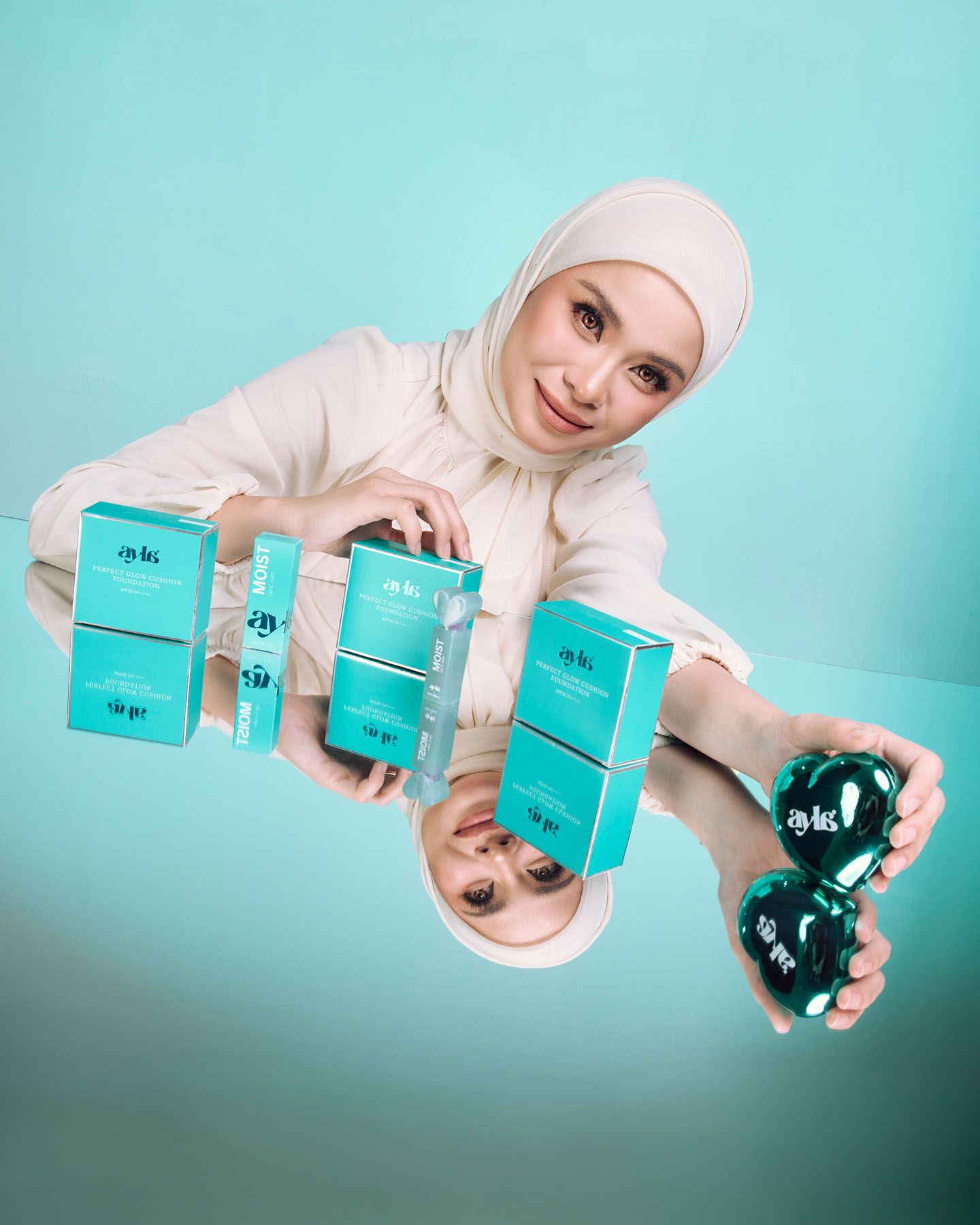 Smiling hijab woman displaying teal skincare product boxes and heart-shaped bottle.