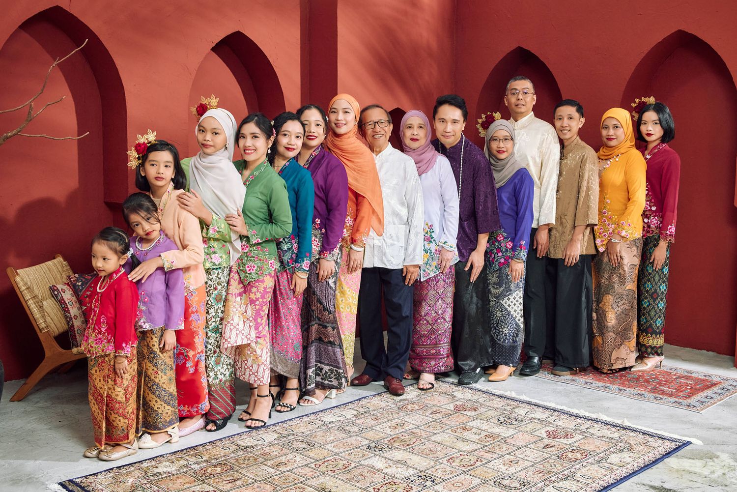 Group of Malaysian women and girls in vibrant traditional Kebaya outfits standing for Raya photo.