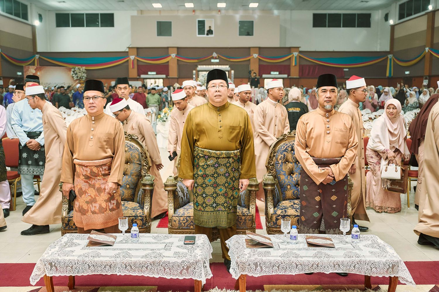 Malaysian dignitaries in traditional Baju Melayu standing formally at an indoor ceremonial hall gathering.