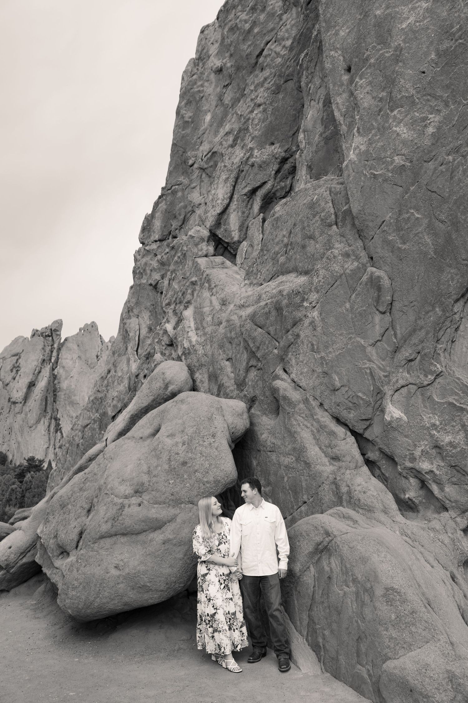 Black and white photo of a couple standing together in front of large rock formations at Garden of the Gods.