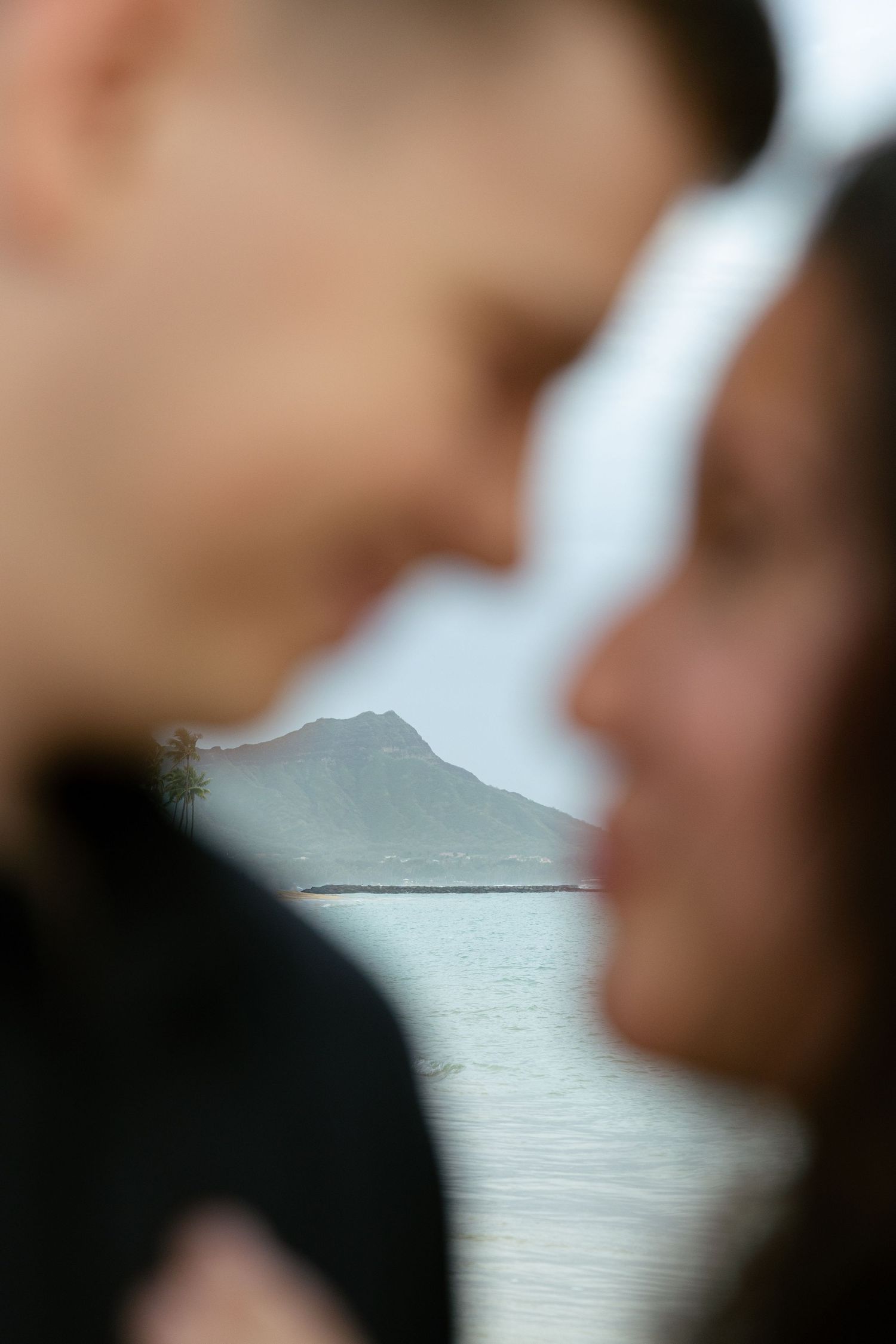 Couple in soft focus with Diamond Head crater and ocean visible between them in Hawaii.