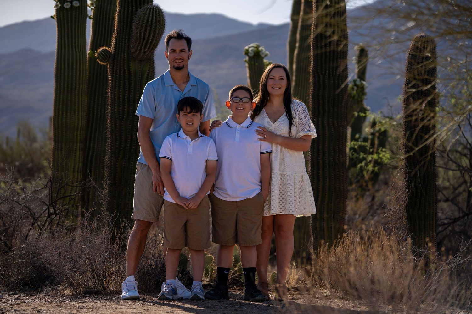 Family standing together in the desert, dressed in western-inspired outfits with warm natural light.