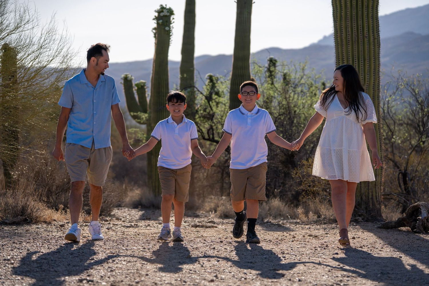Family holding hands and walking together through the desert during a golden sunset in Tucson, Arizona.