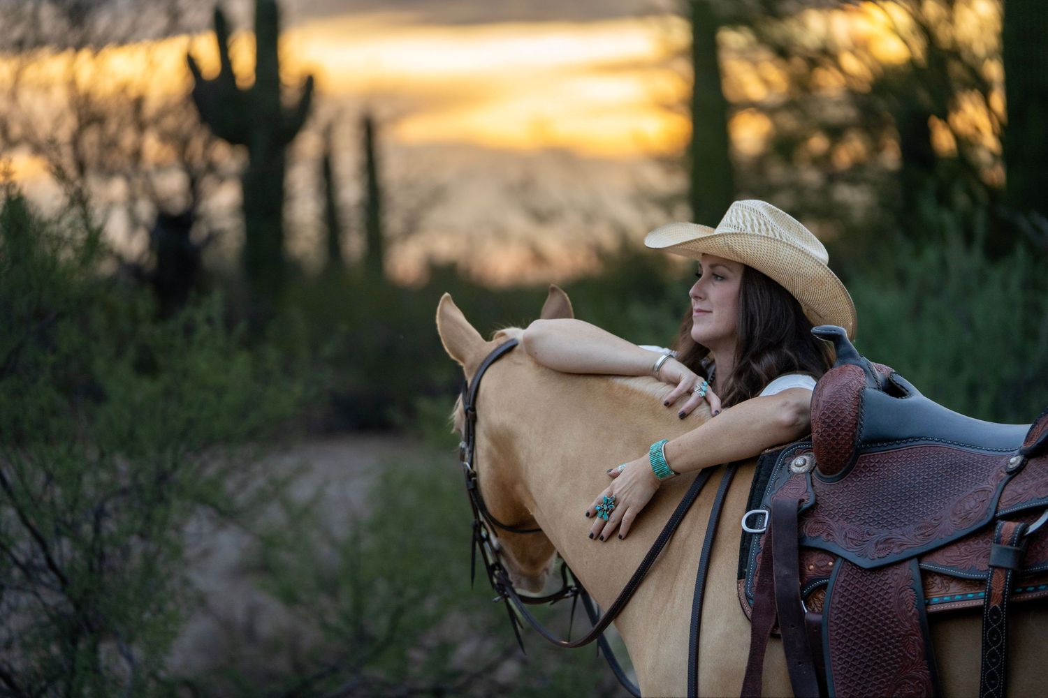 Cowgirl leaning on her horse in the golden hour desert