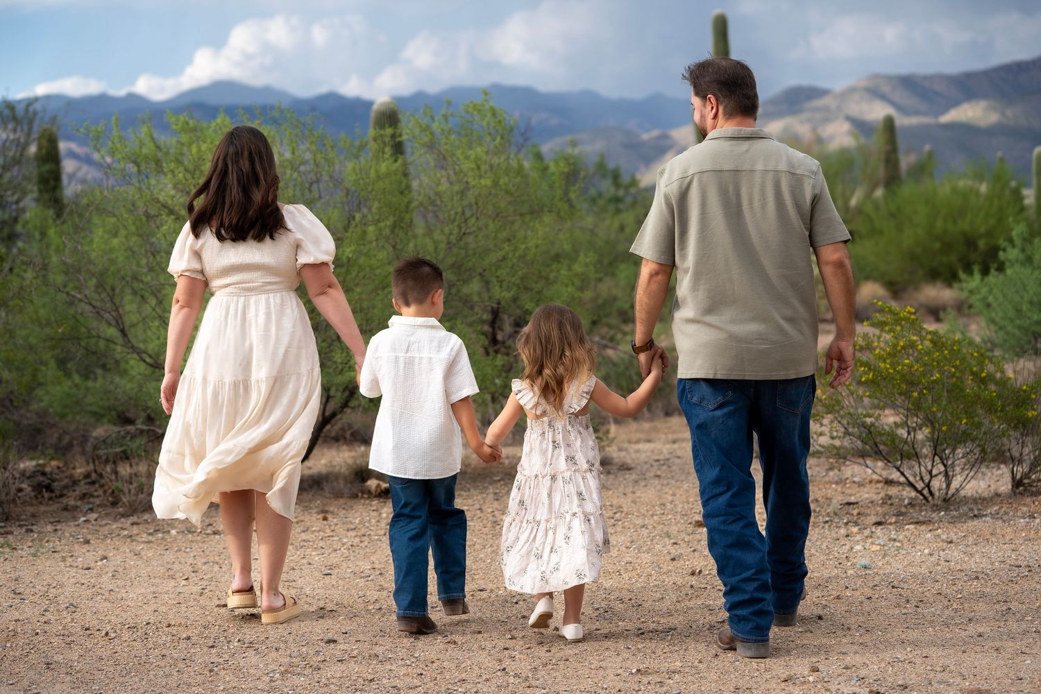 Family holding hands and walking away from the camera through the desert in Tucson, Arizona.