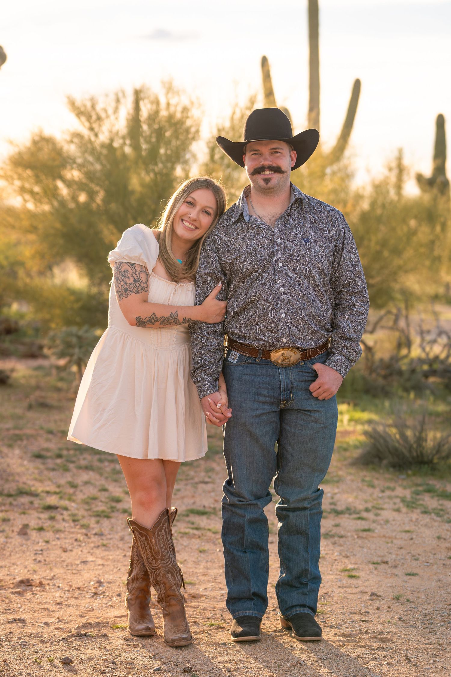 Western couple portrait at sunset in Arizona desert with saguaro cacti, engagement photography