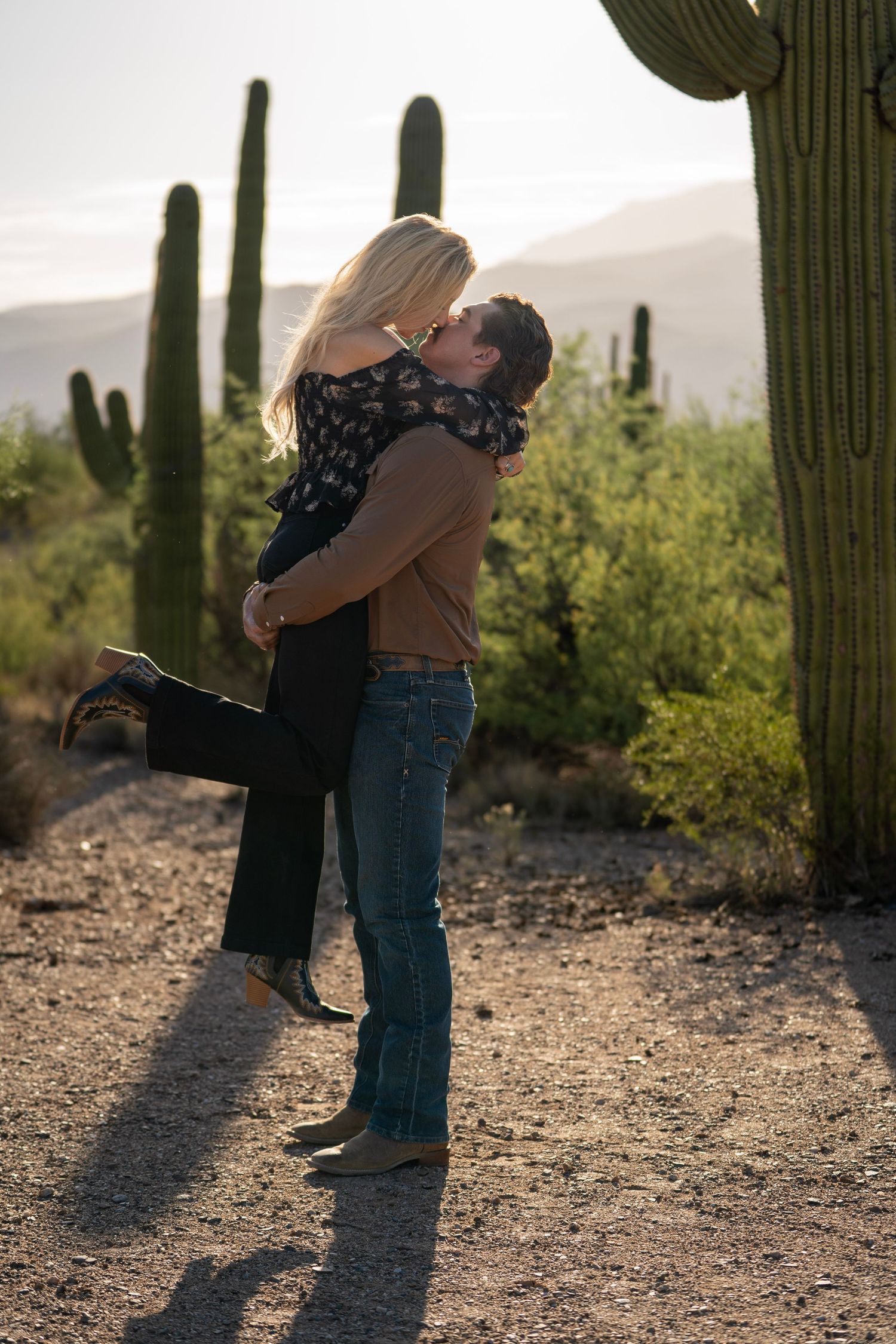 Man lifting his partner in an embrace during a western couple photoshoot in the Arizona desert.