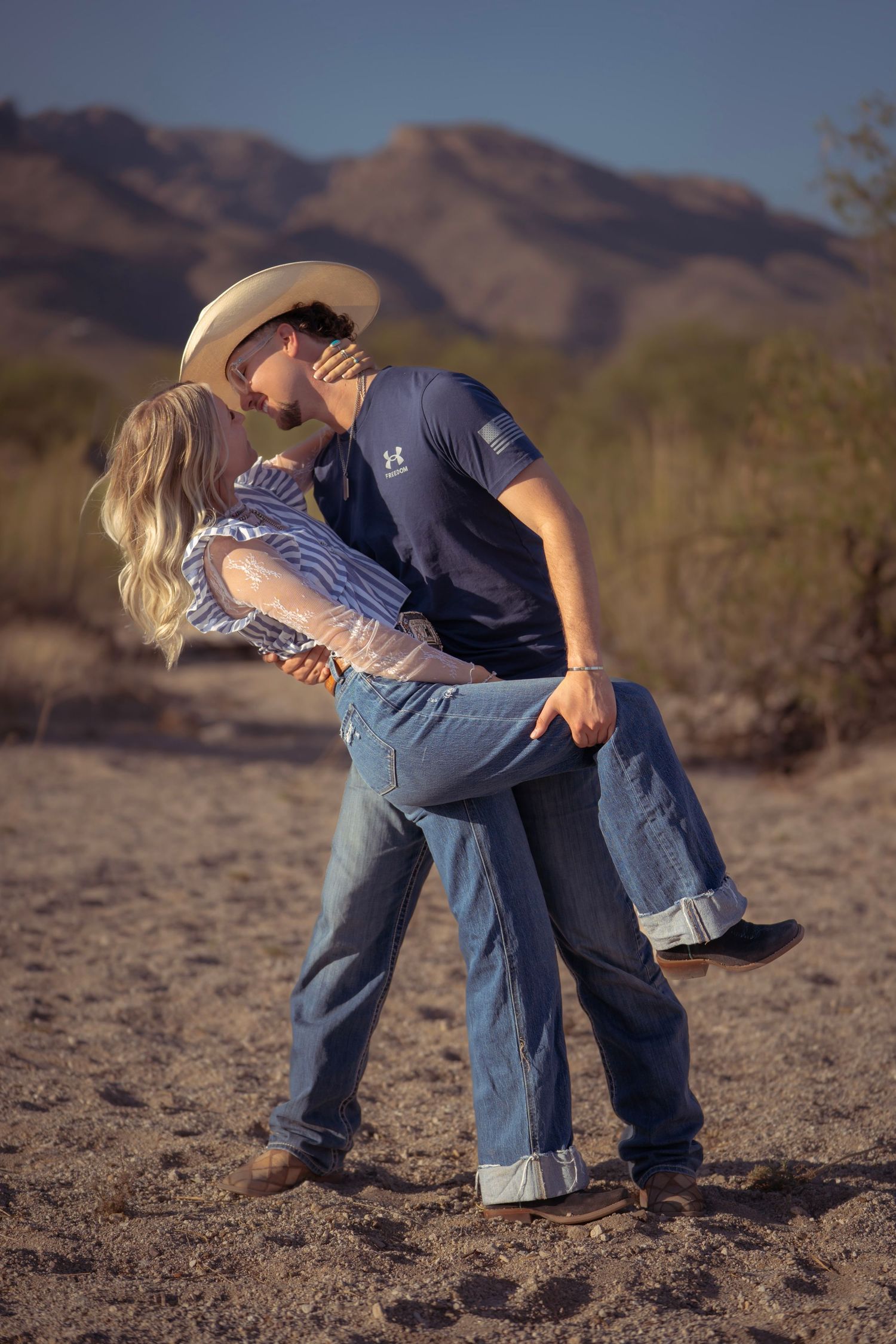 Man dipping his partner and kissing her during a western-style dance in the Arizona desert at sunset.