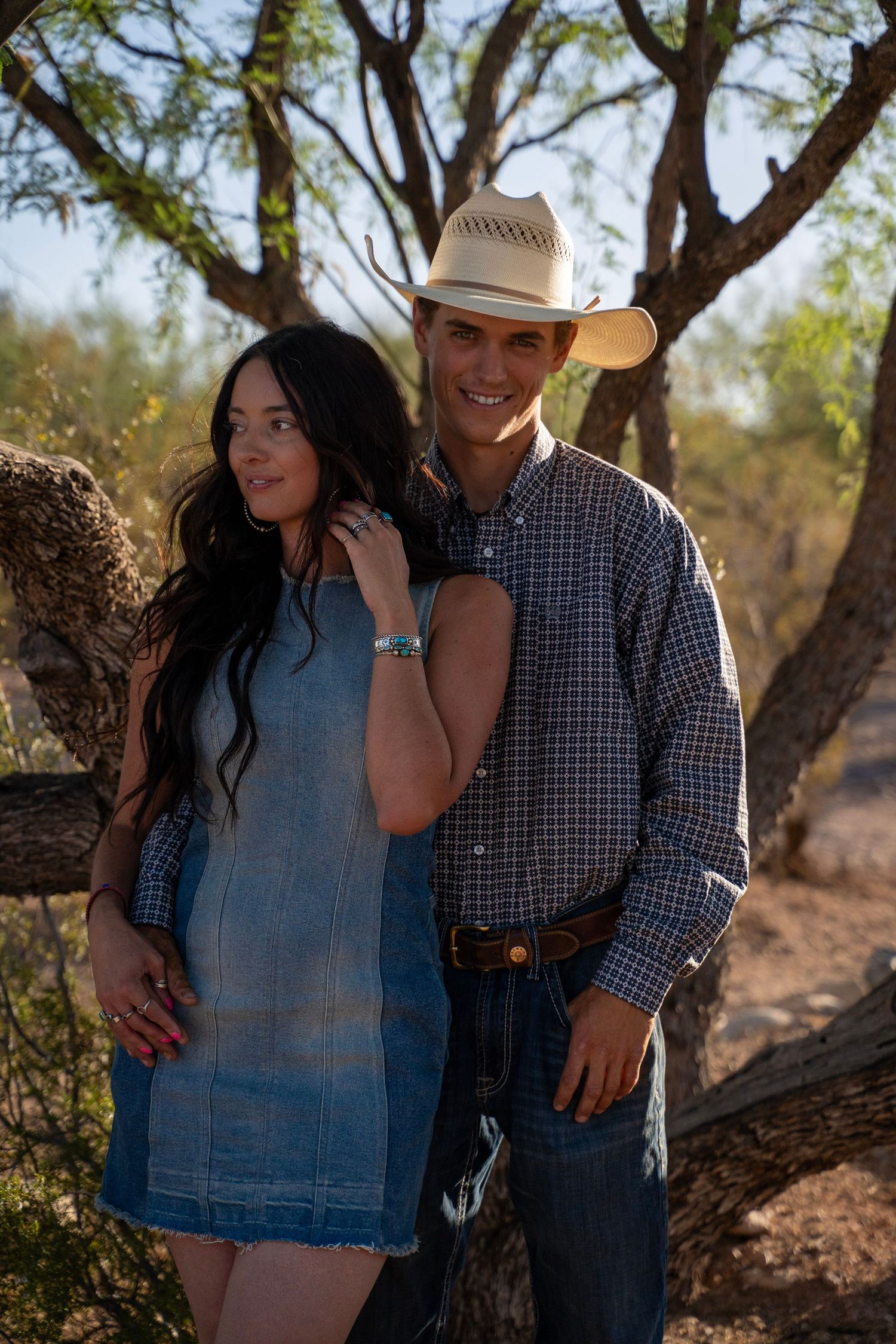 Couple dressed in western outfits embracing in a rustic desert setting near Tucson.