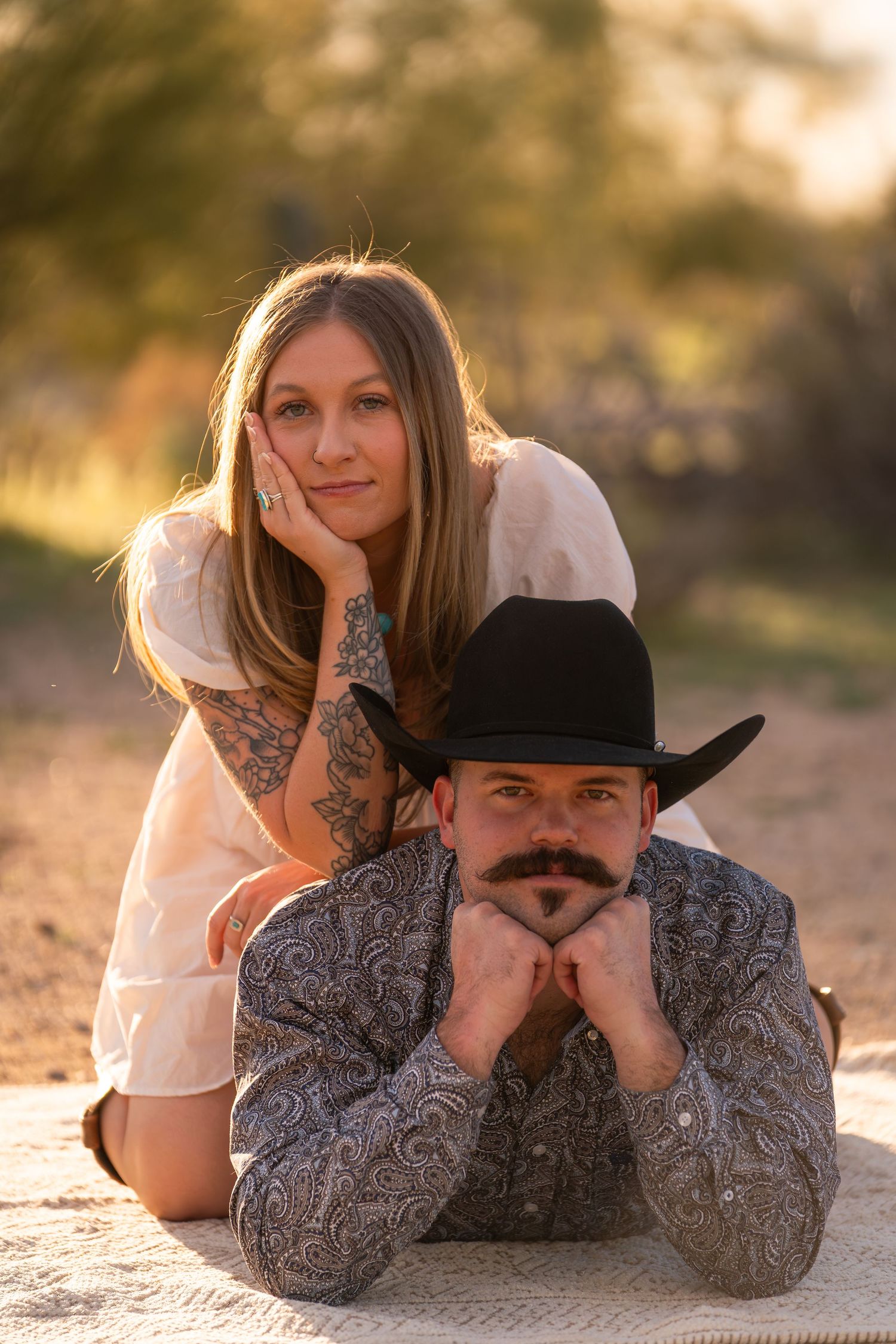 Western couple portrait at sunset in Arizona desert, cowboy hat and golden hour engagement photography.