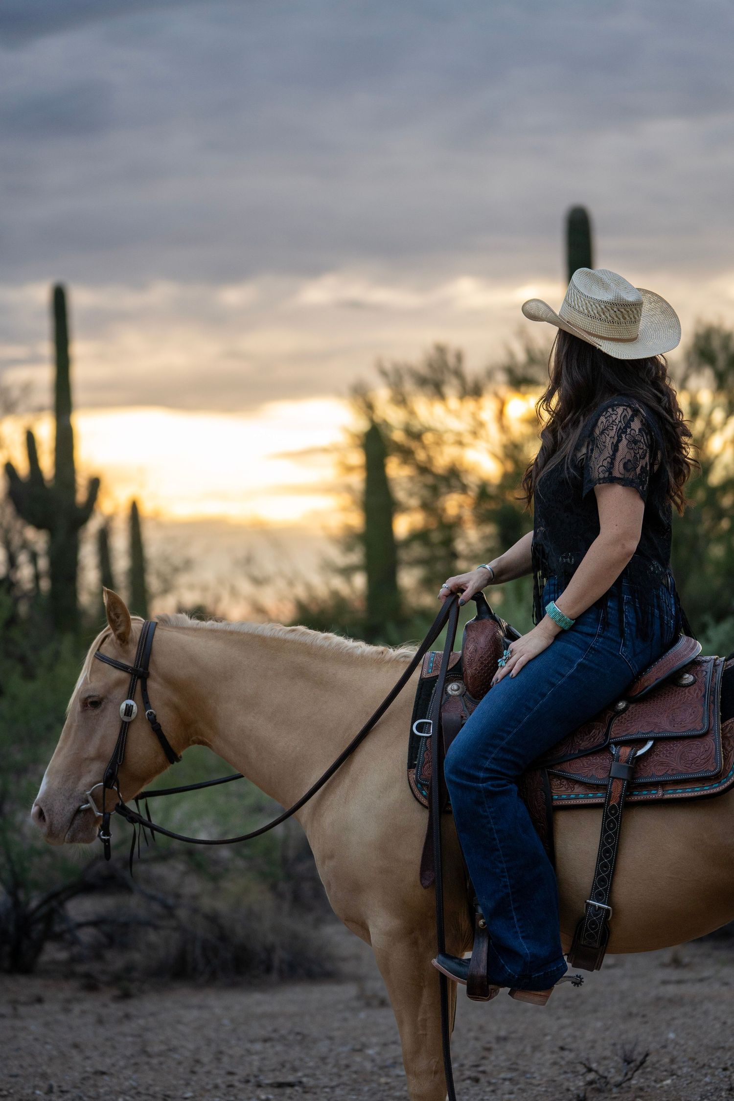 Cowgirl sitting on her horse in the golden hour sunset