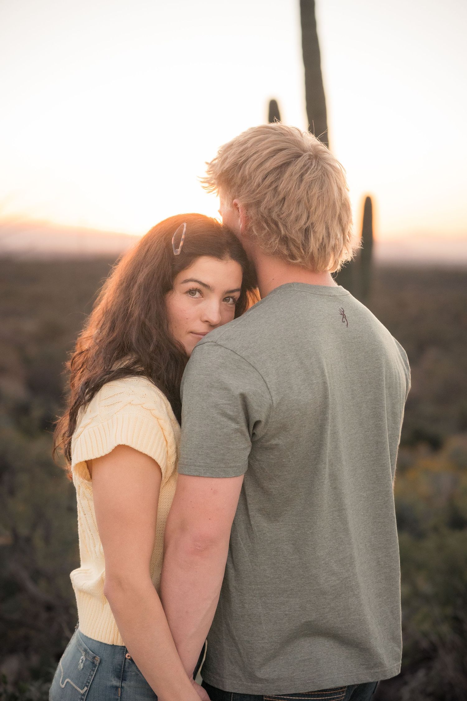 Intimate couple portrait at sunset in Arizona desert with saguaro silhouettes, romantic engagement photography.