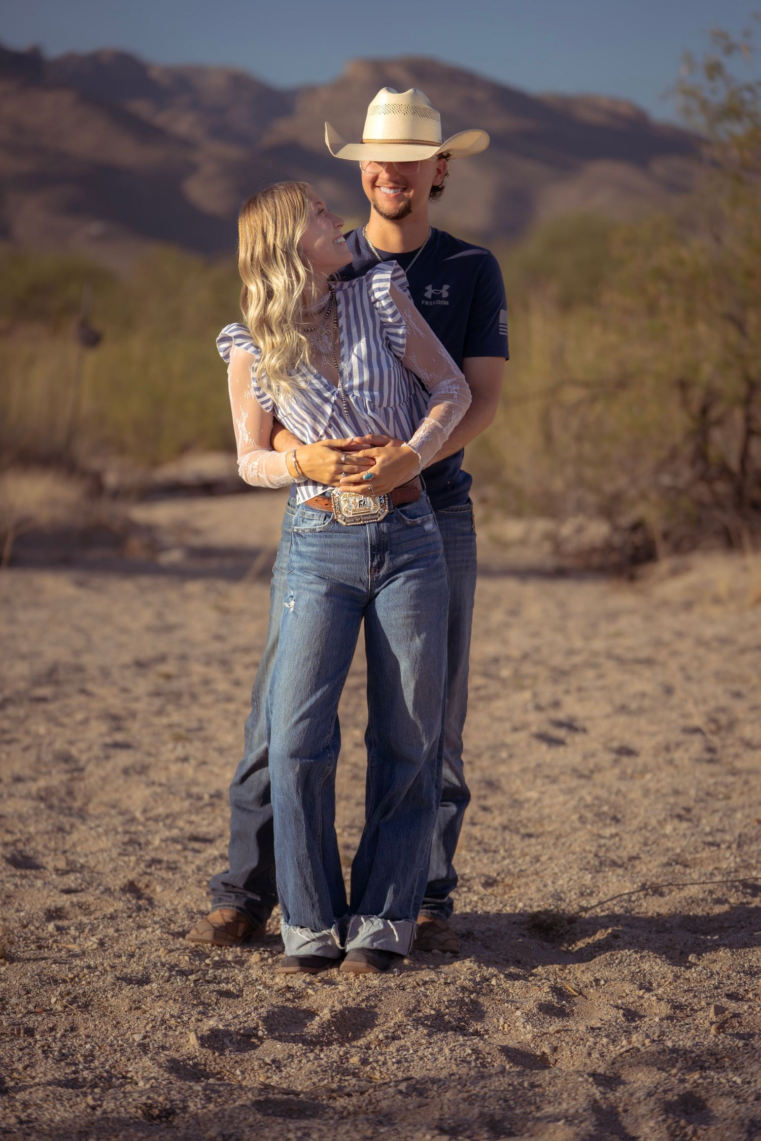 Couple holding each other closely during a romantic western photoshoot in the Tucson desert.