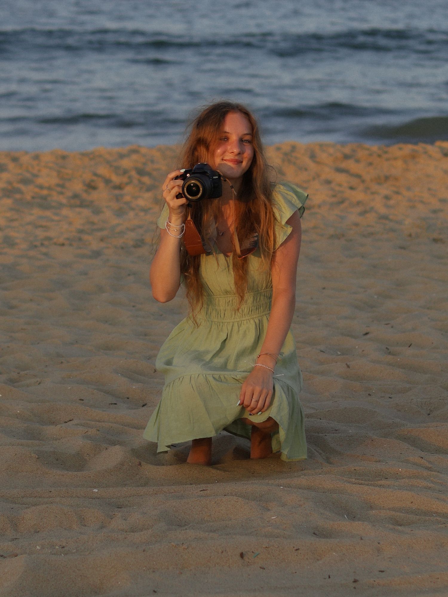 photographer holding camera and squatting at the beach