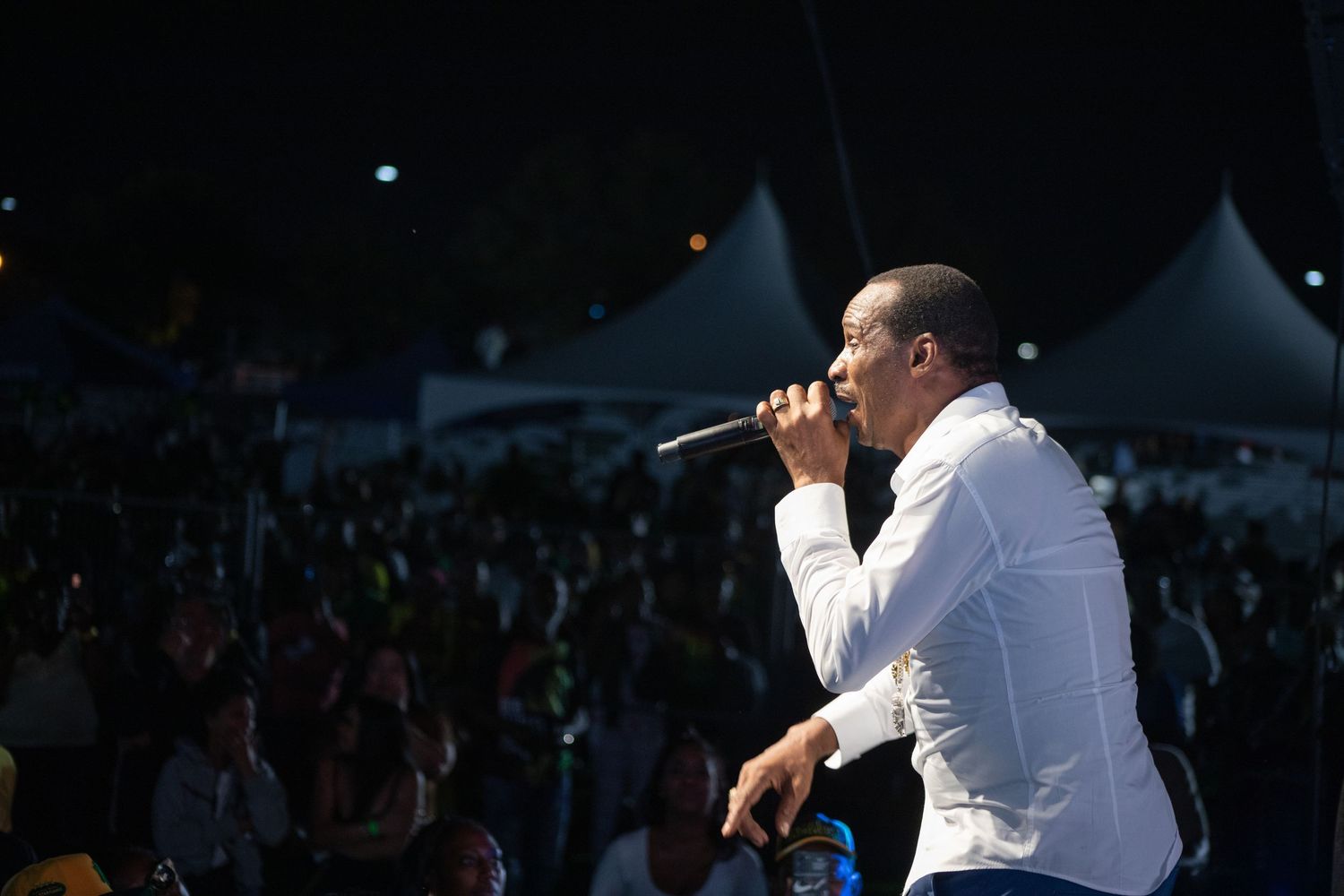 Jamaican singer Sanchez lit by the spotlight, holding a microphone in his left hand while serenading the dark crowd of Jamaica Day Toronto.