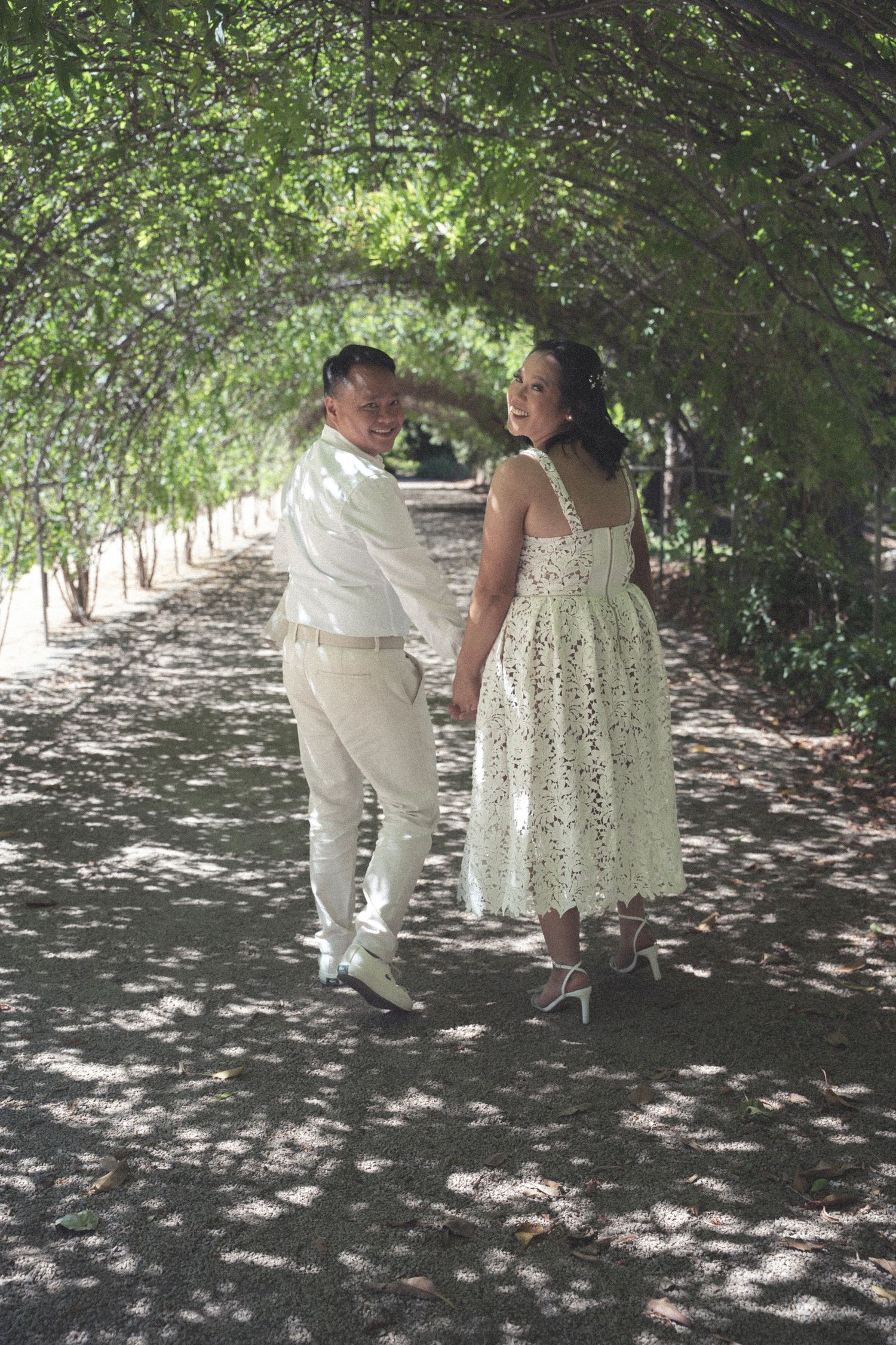 Couple walking hand-in-hand through a lush botanical garden in Adelaide
