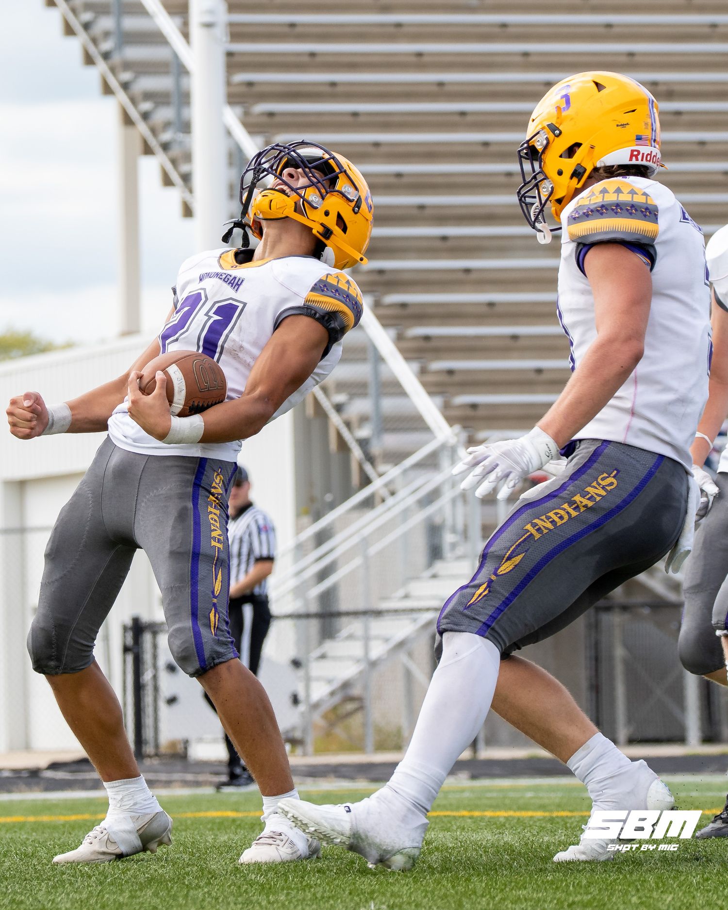 Football players in navy and gold uniforms crouch in formation during a practice drill.