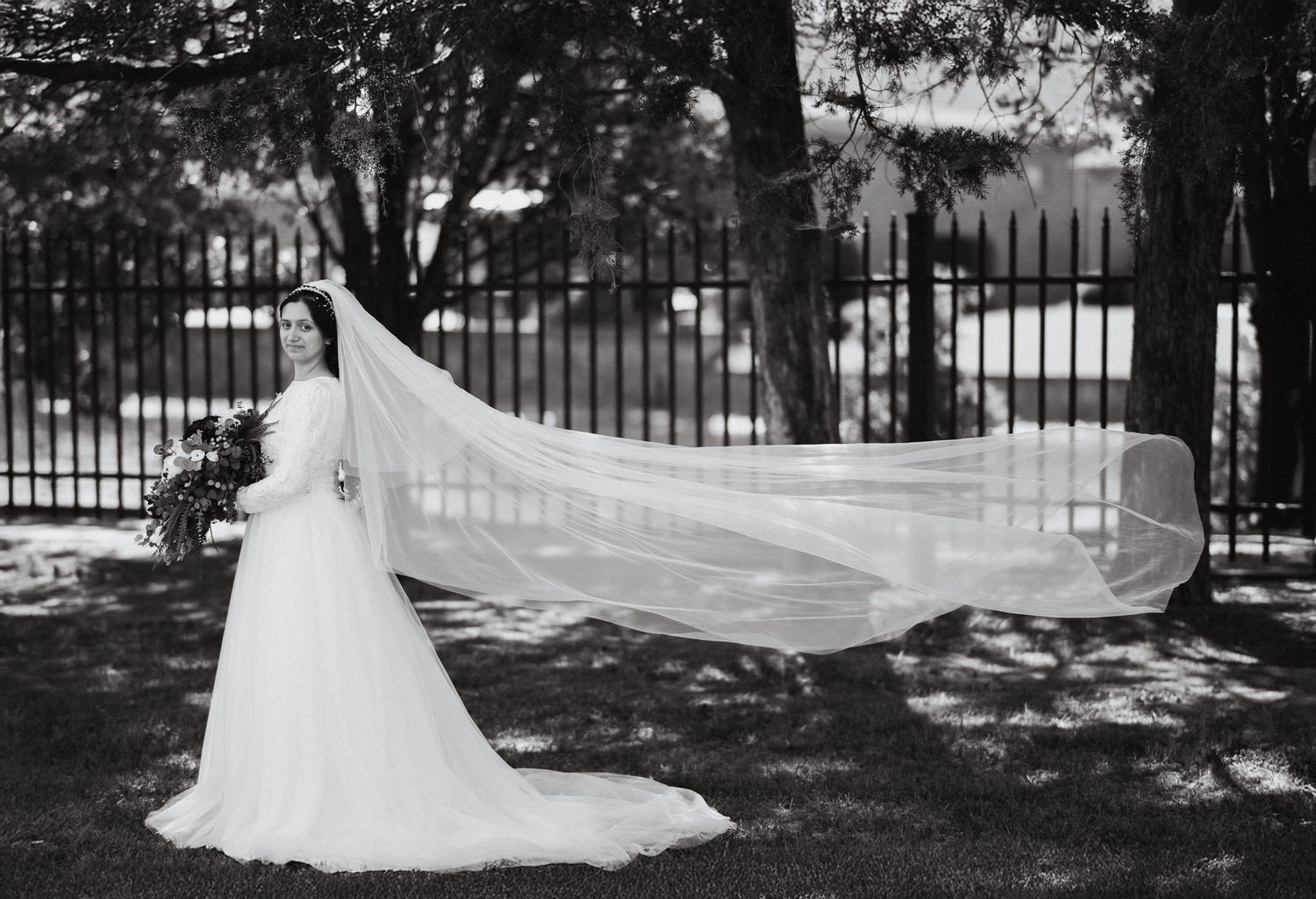 Black and white wedding photographs showing dramatic veil and dress silhouettes in a park setting.
