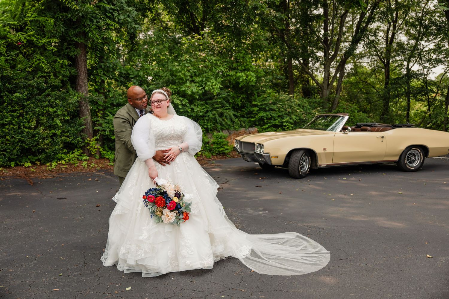 Wedding couple posing in various romantic positions on grass with vintage car visible in background.