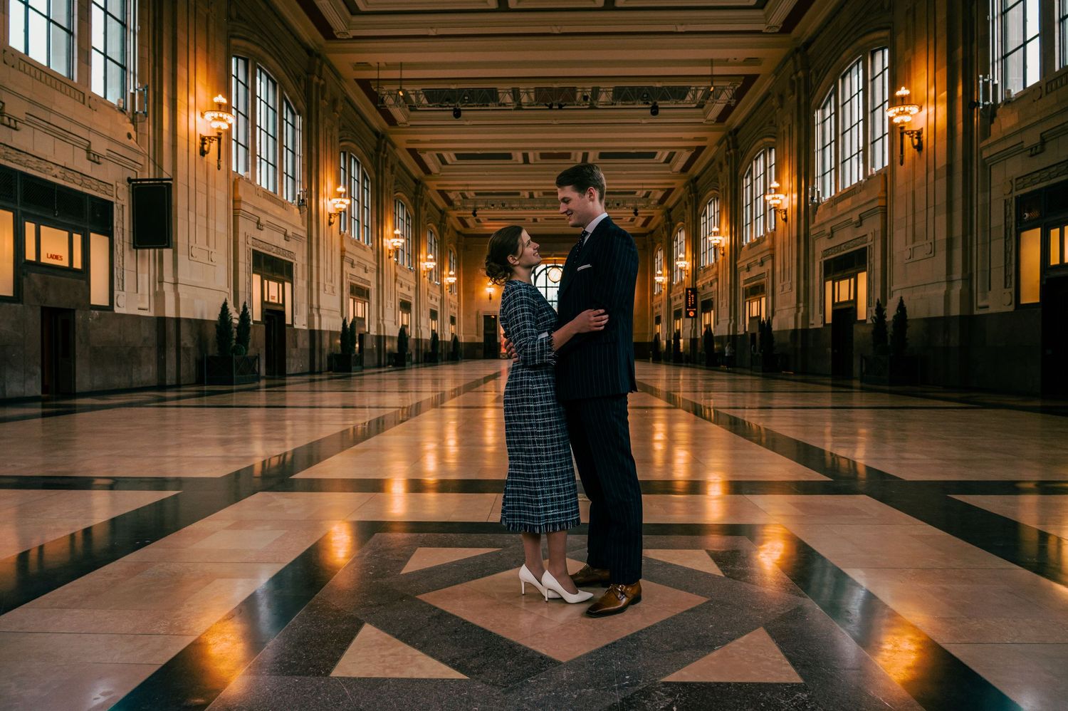 Romantic indoor wedding portraits in grand hallway with beautiful architectural lighting and reflective floors.