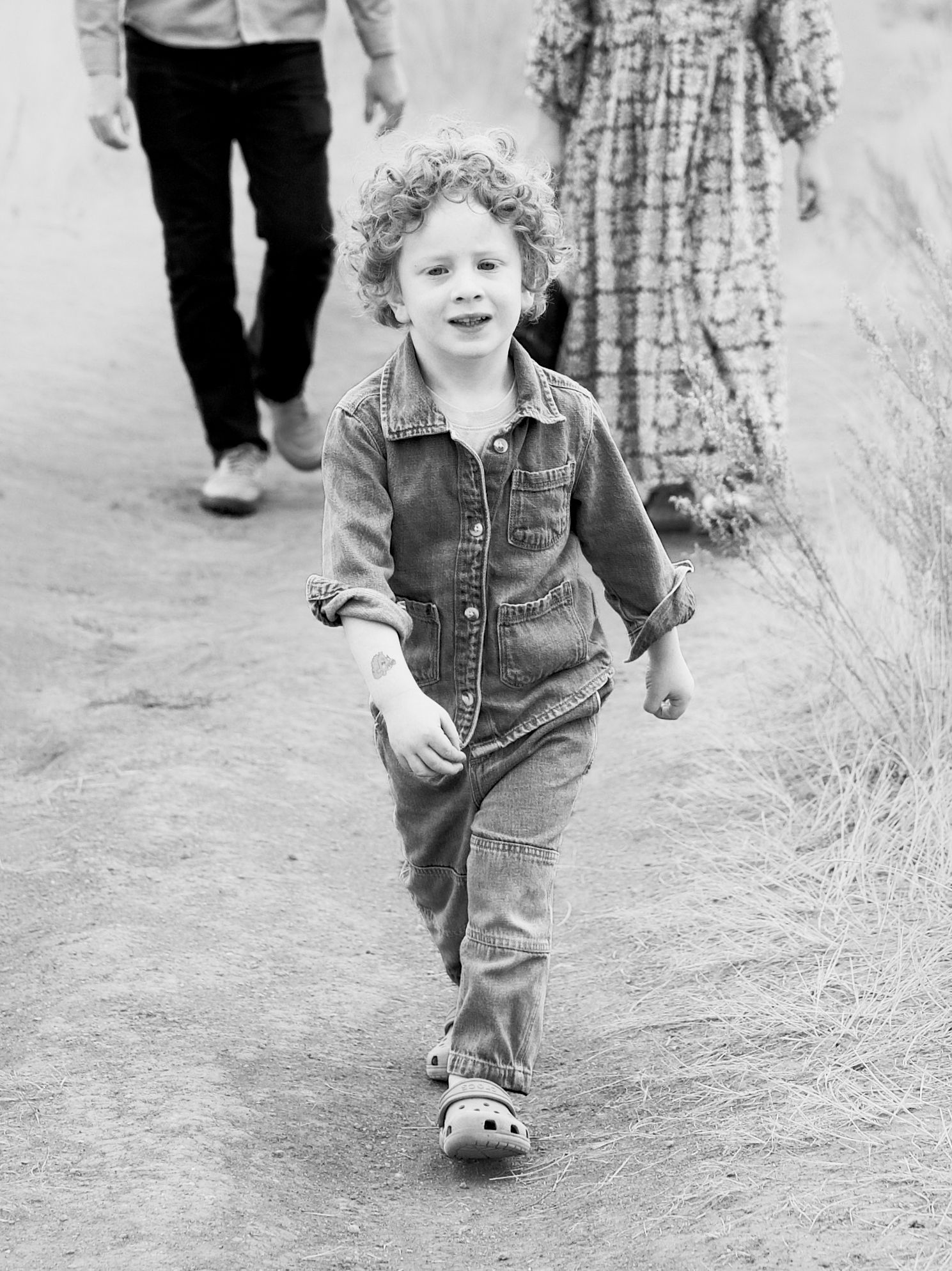 A black and white portrait of a kid walking with his parents. Taken at Lory State Park near Bellevue or Fort Collins, Colorado.