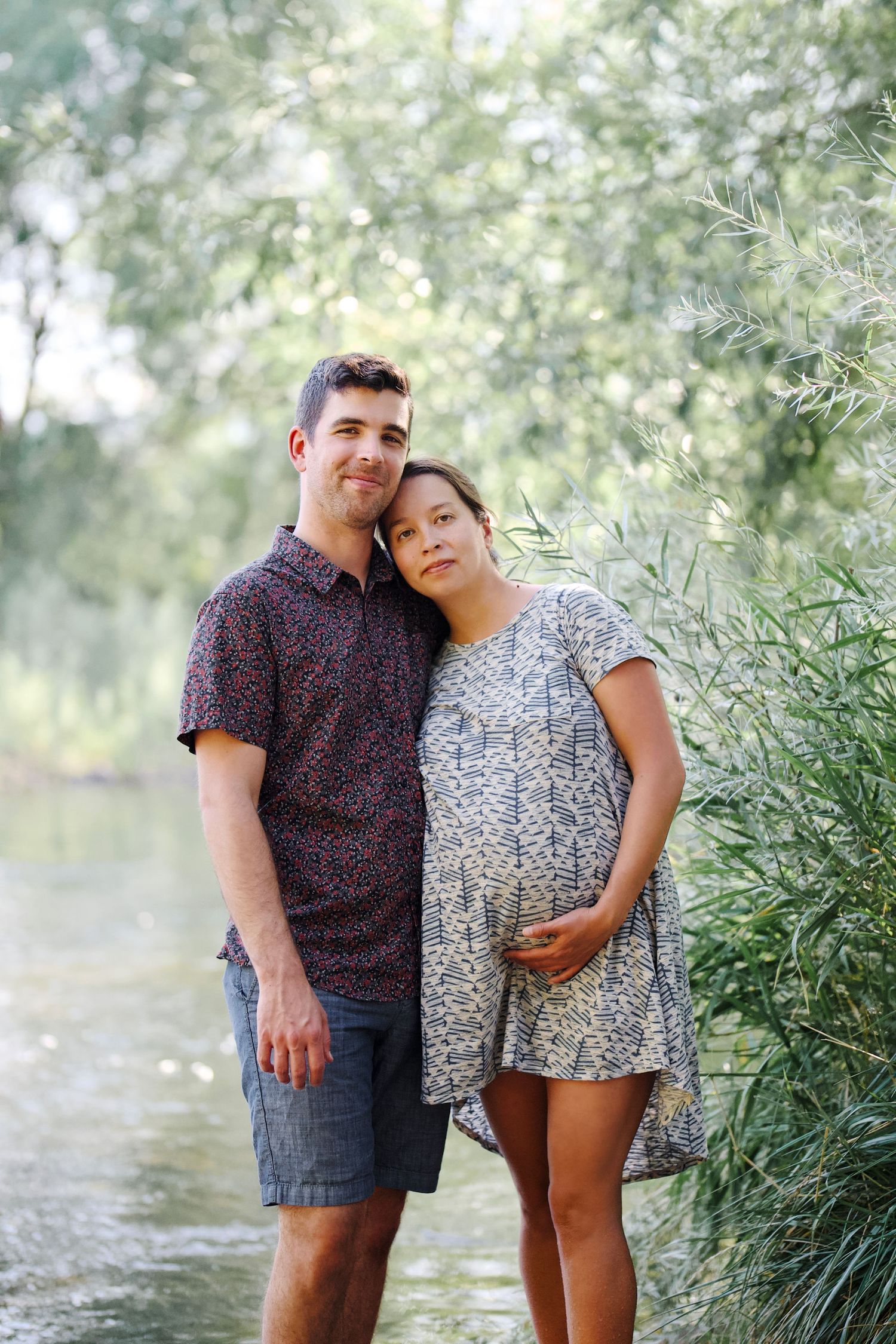 A portrait of a married couple outdoors with trees in the background by the Poudre River in Fort Collins, Colorado.