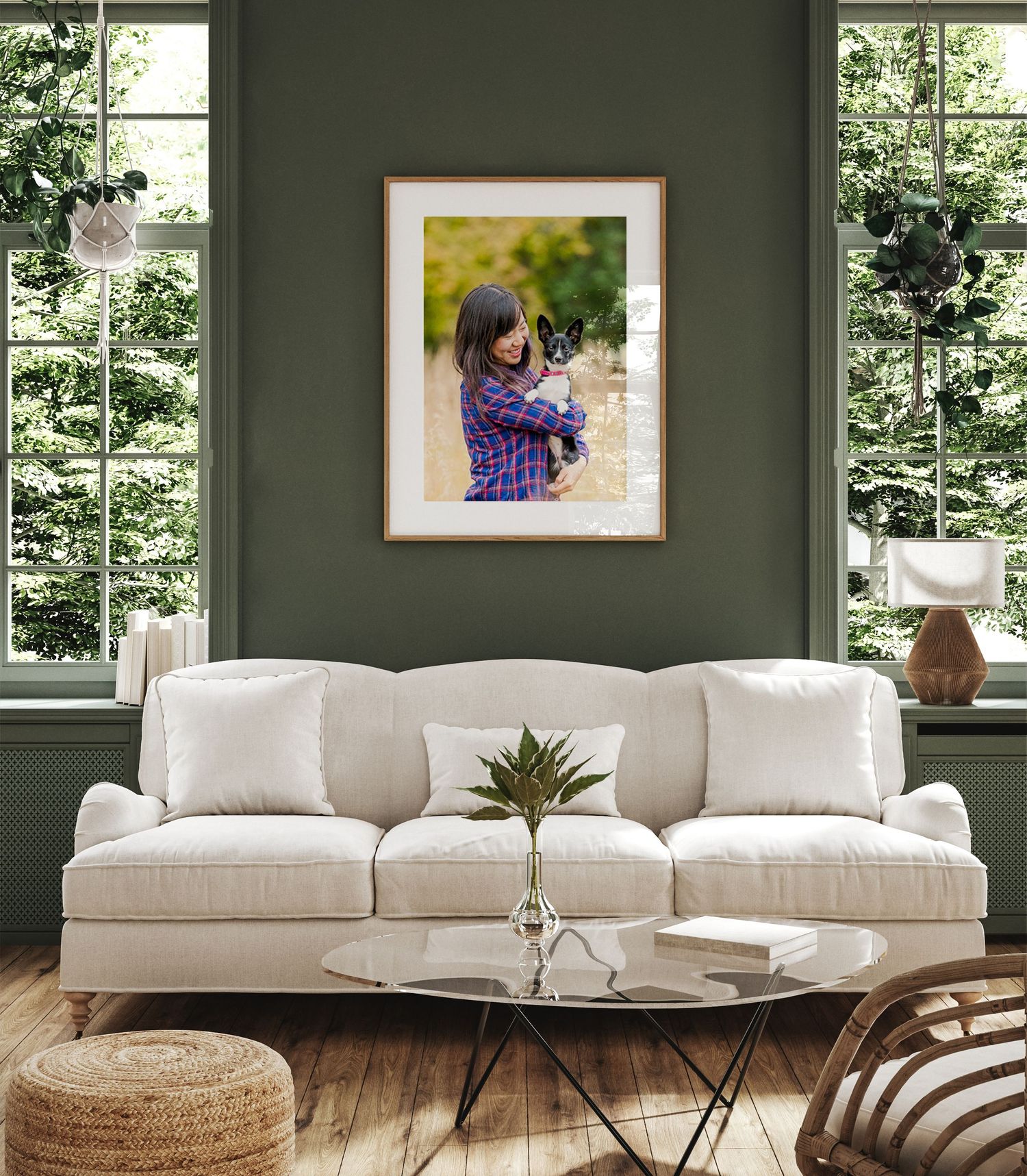 Modern living room with white sectional sofa, glass coffee table and dark green walls with framed artwork.