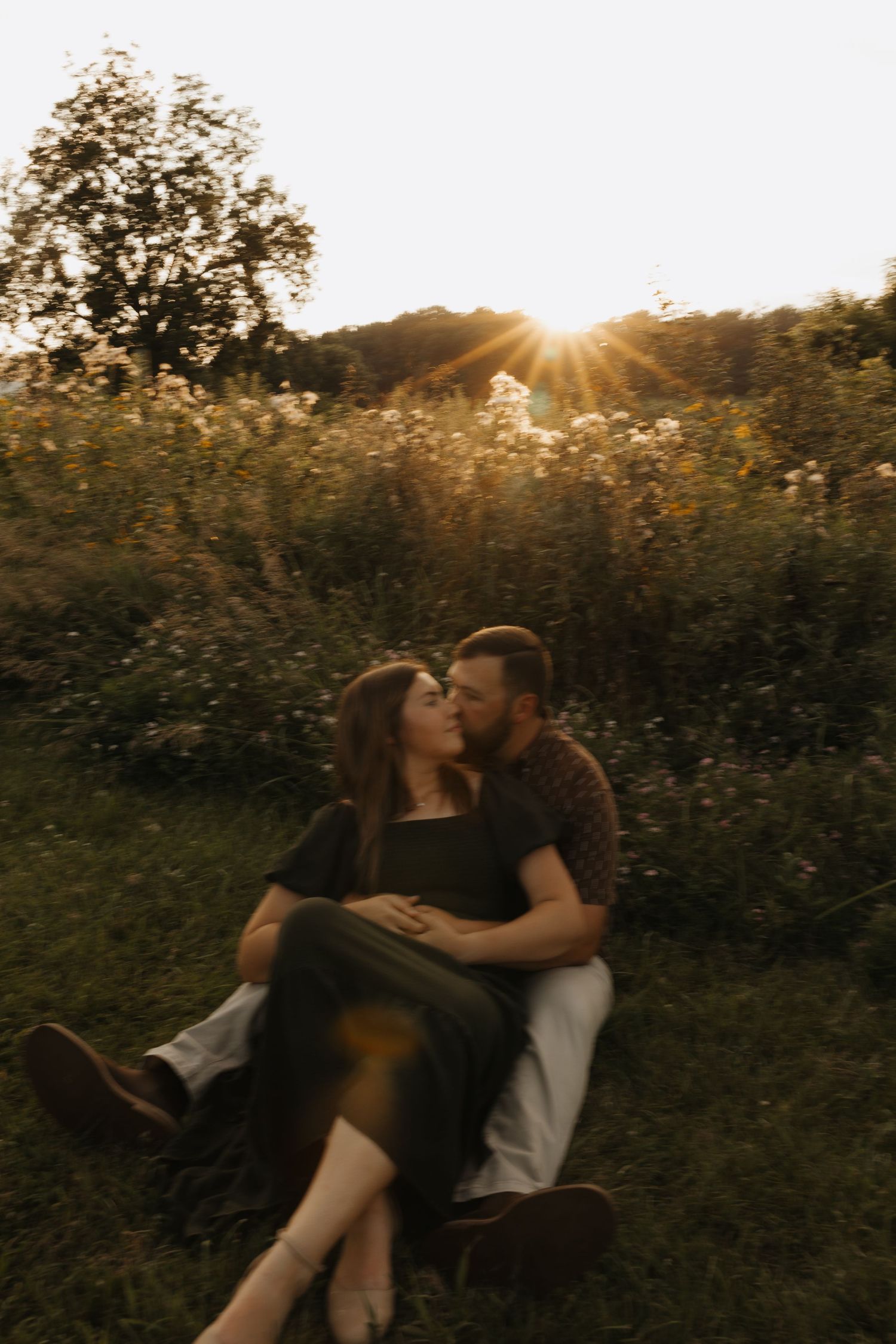 A romantic sunset moment in a wildflower meadow with golden sunbeams streaming through trees in the background.