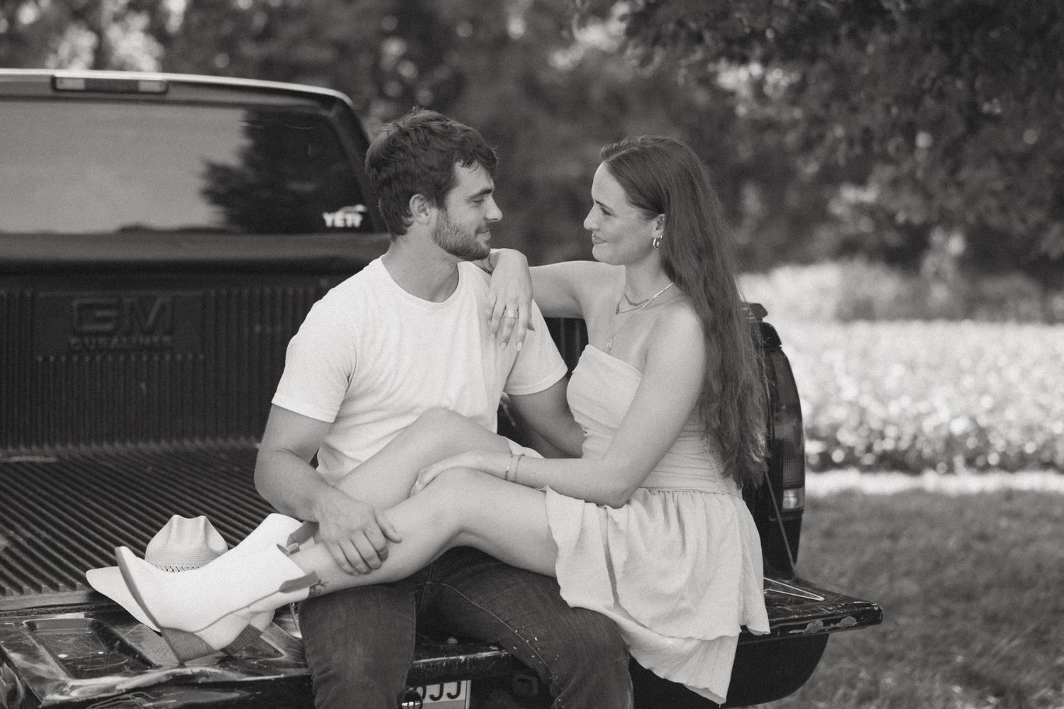 Couple sharing tender moments in black and white photography near a vintage truck.