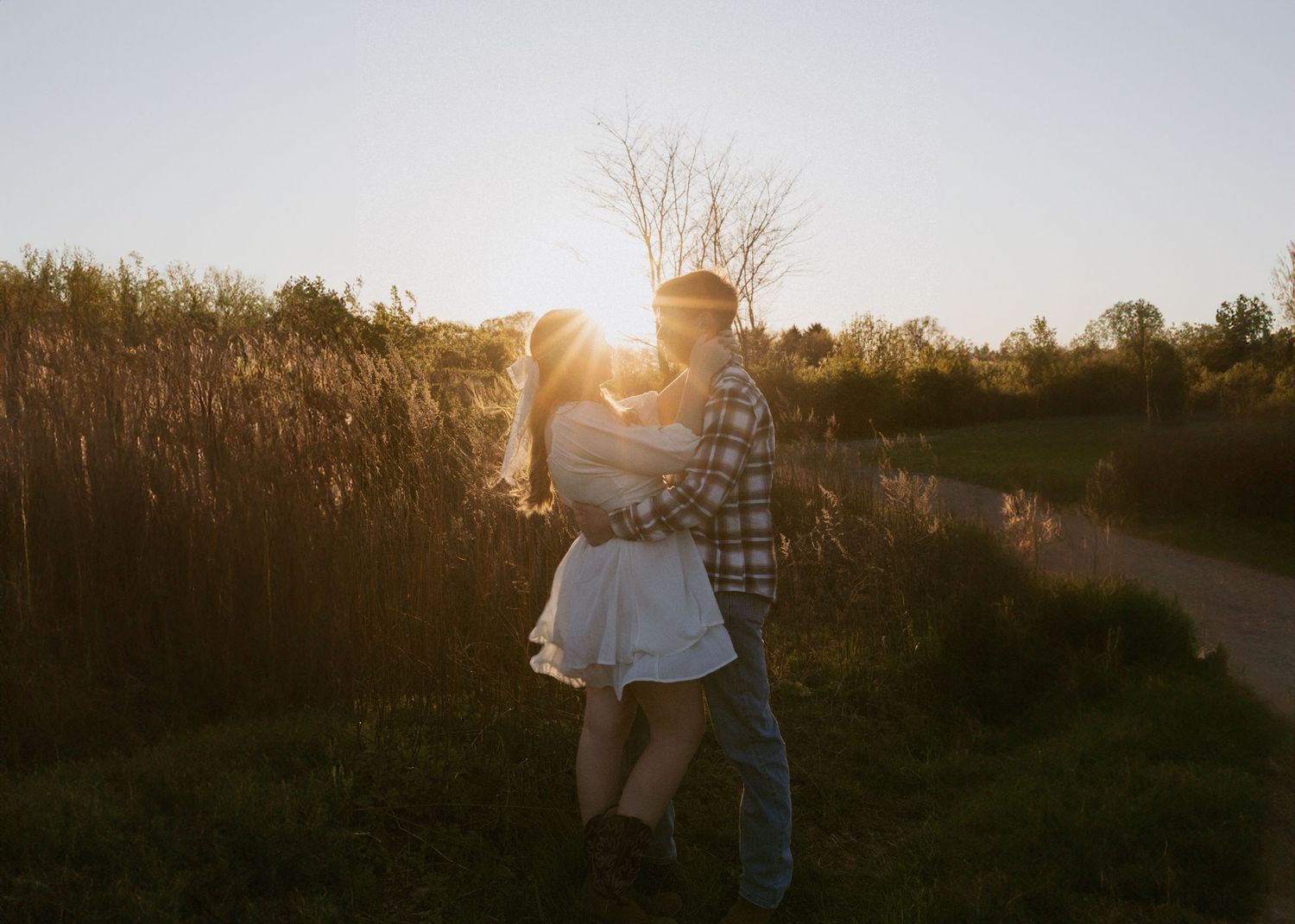 Silhouettes against a golden sunset in a rural field setting.
