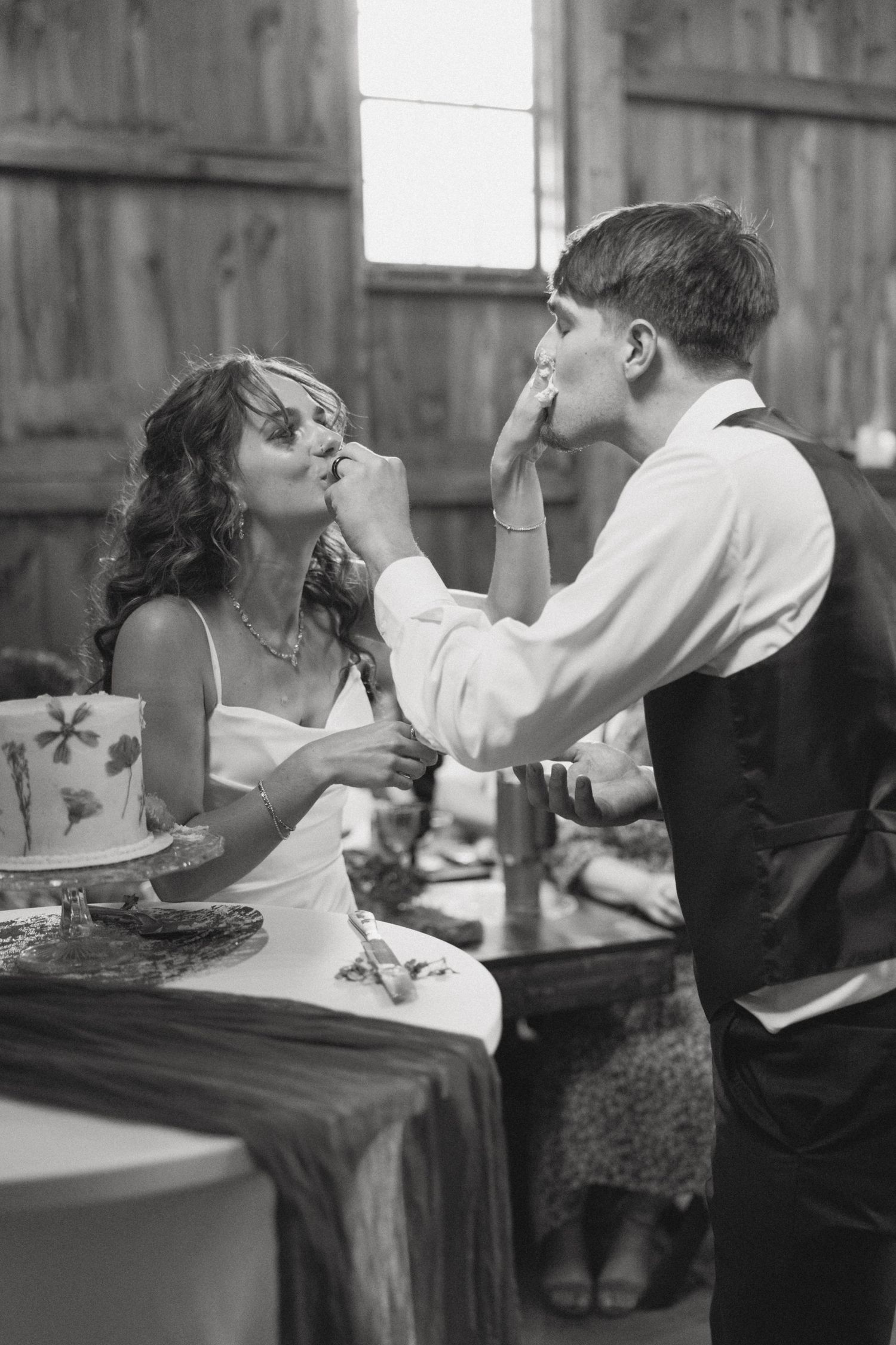 Black and white sequence of playful cake feeding moments at a wedding reception.