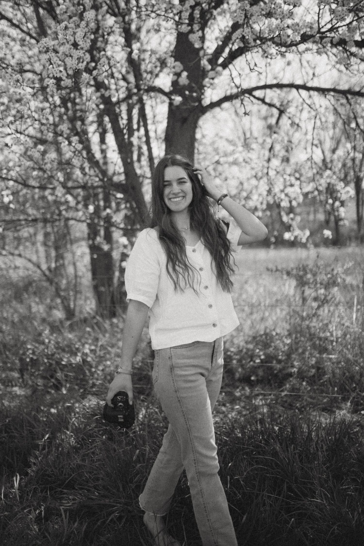 Spring photoshoot in a blooming orchard with white blossoms and natural lighting.