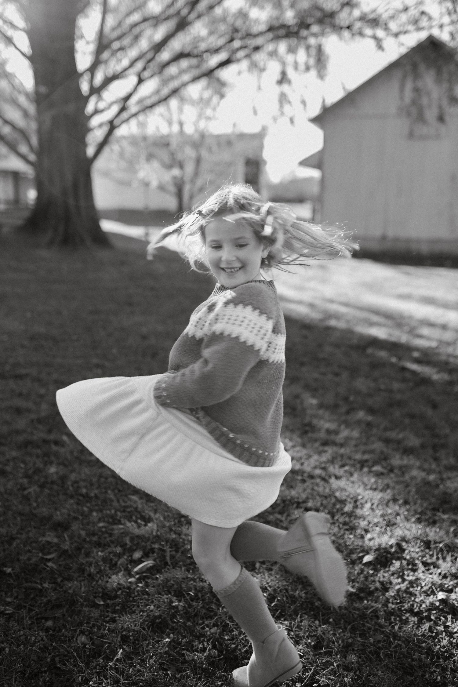 Black and white photos of a flowing white dress twirling in a grassy field on a sunny day.