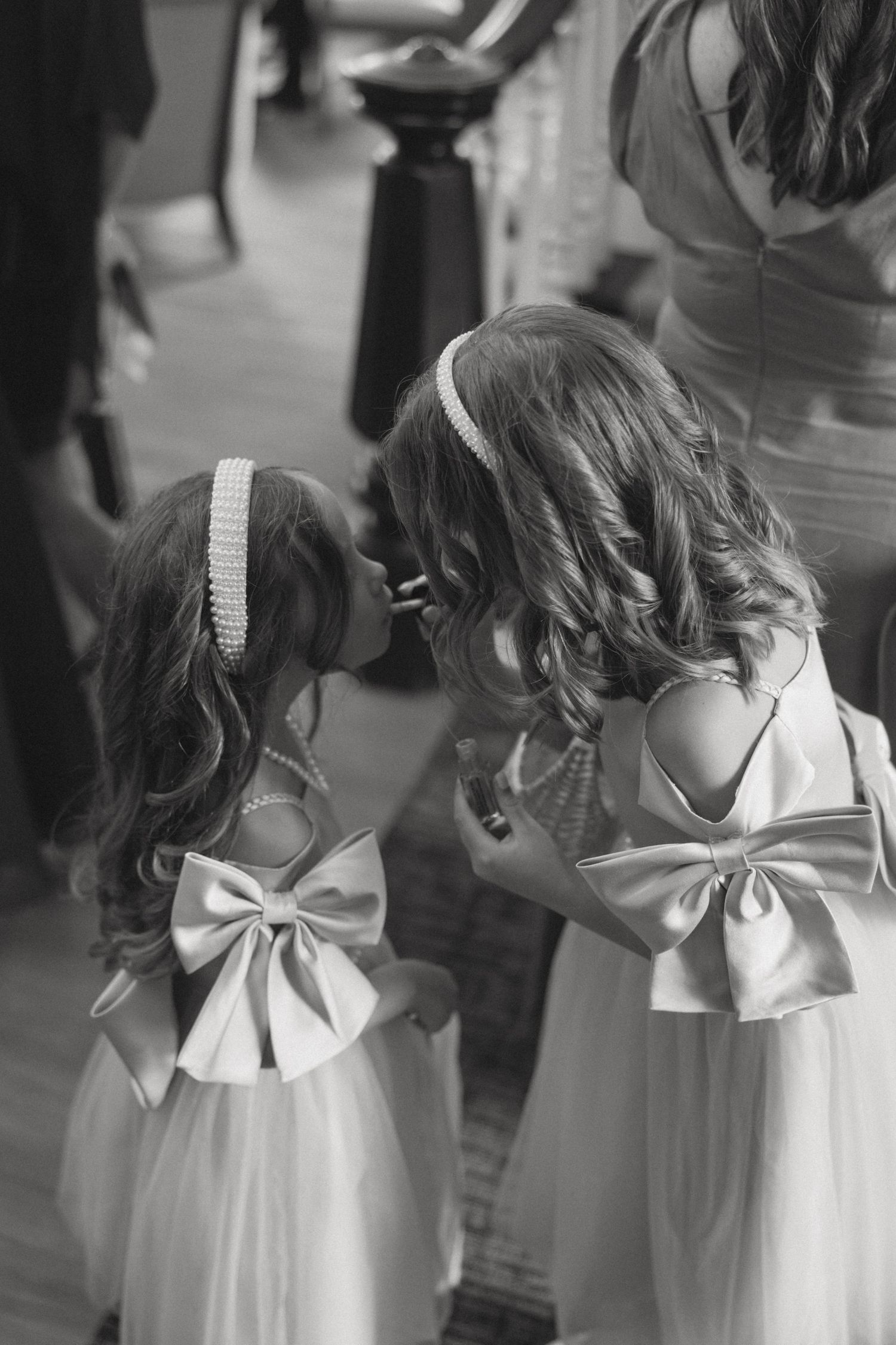 Row of white dresses with elegant bow details shown from behind in black and white.