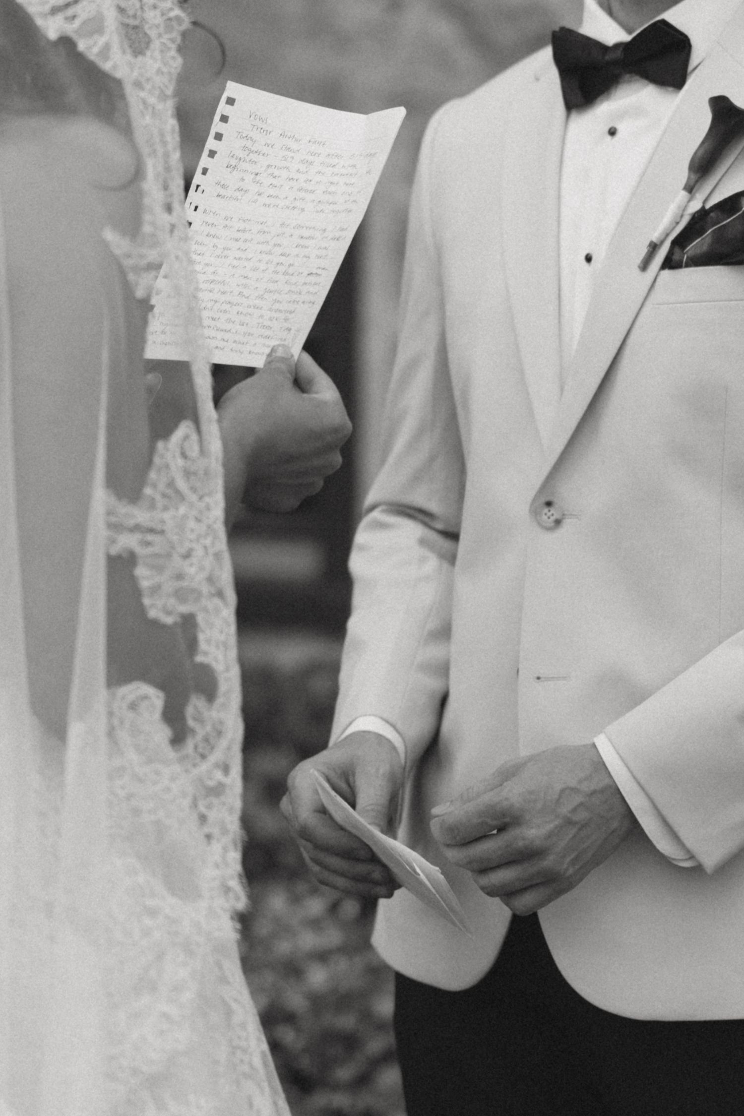 Black and white photo of couple reading handwritten vows during wedding ceremony.