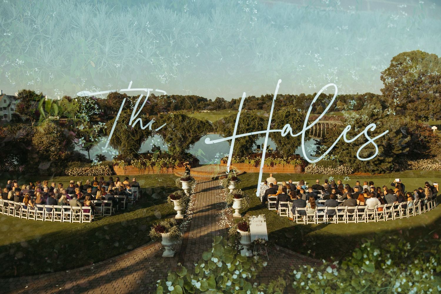 A rustic outdoor wedding ceremony setup with white chairs and wooden arbor in a scenic countryside setting.
