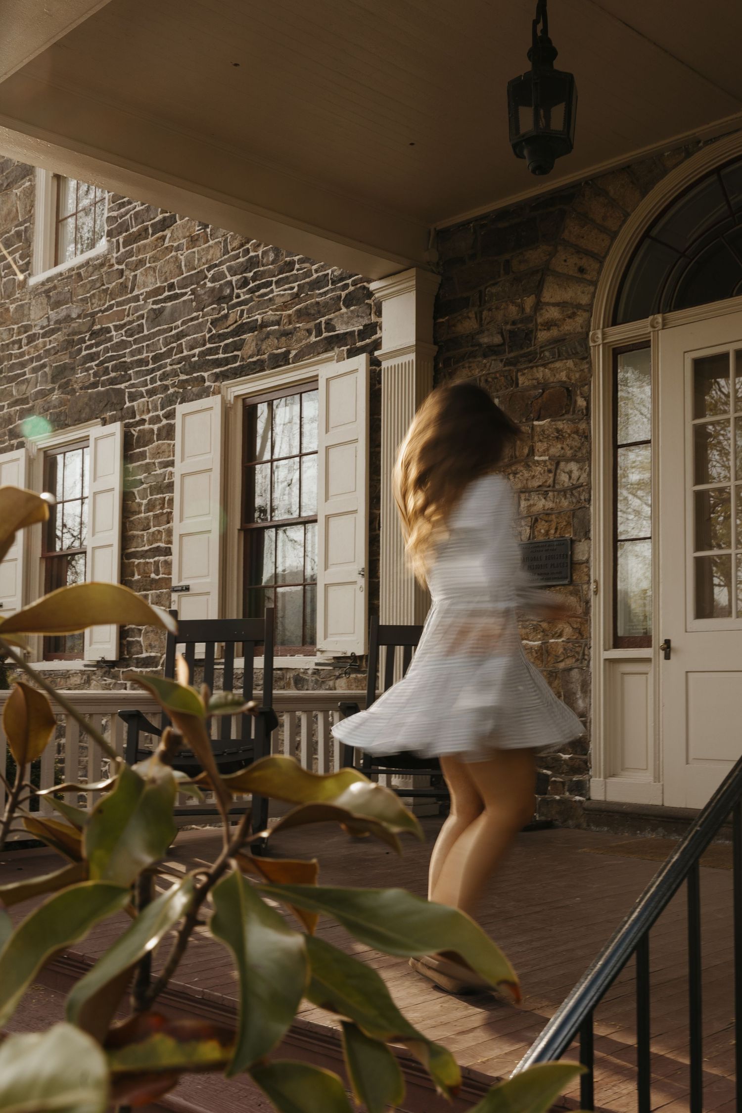 A sequence of motion-blurred images showing someone spinning in a white dress on a stone porch with rocking chairs.